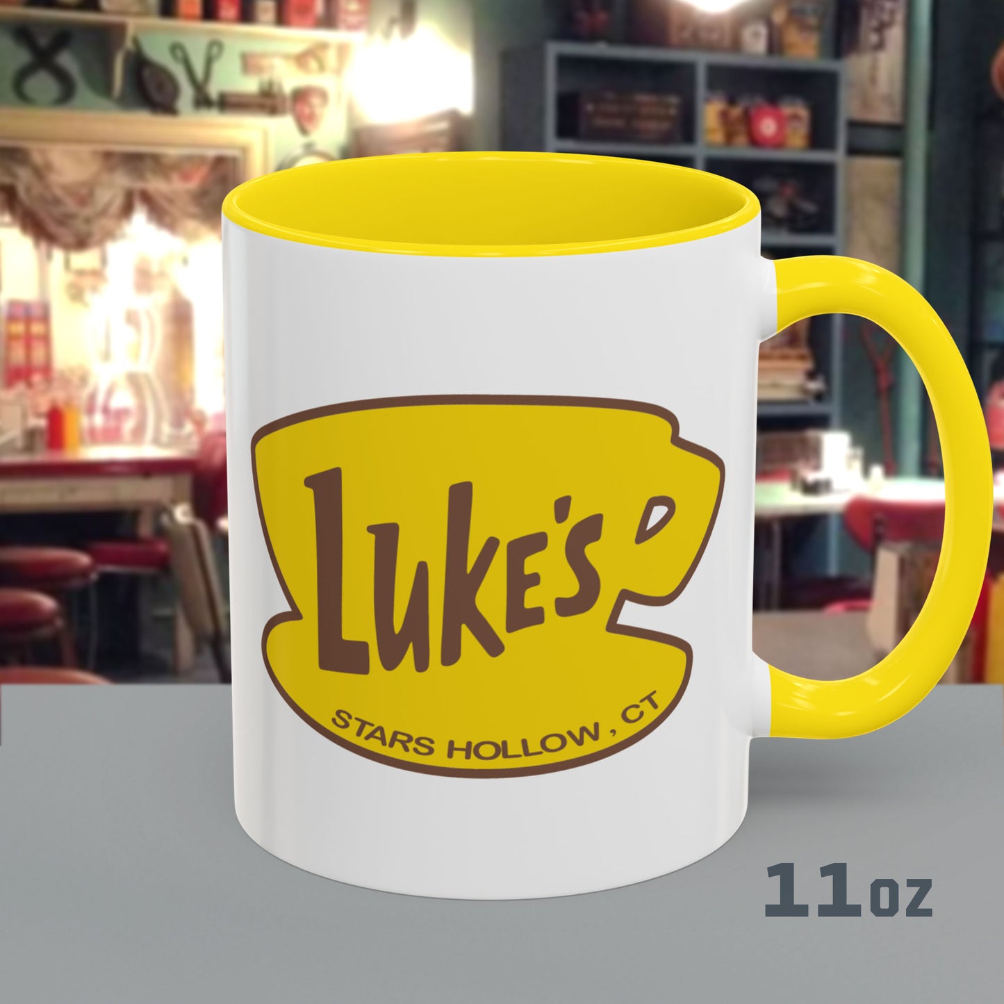 Front view of 11 oz White ceramic mug with yellow handle and Luke’s Diner logo from Gilmore Girls printed on both sides.