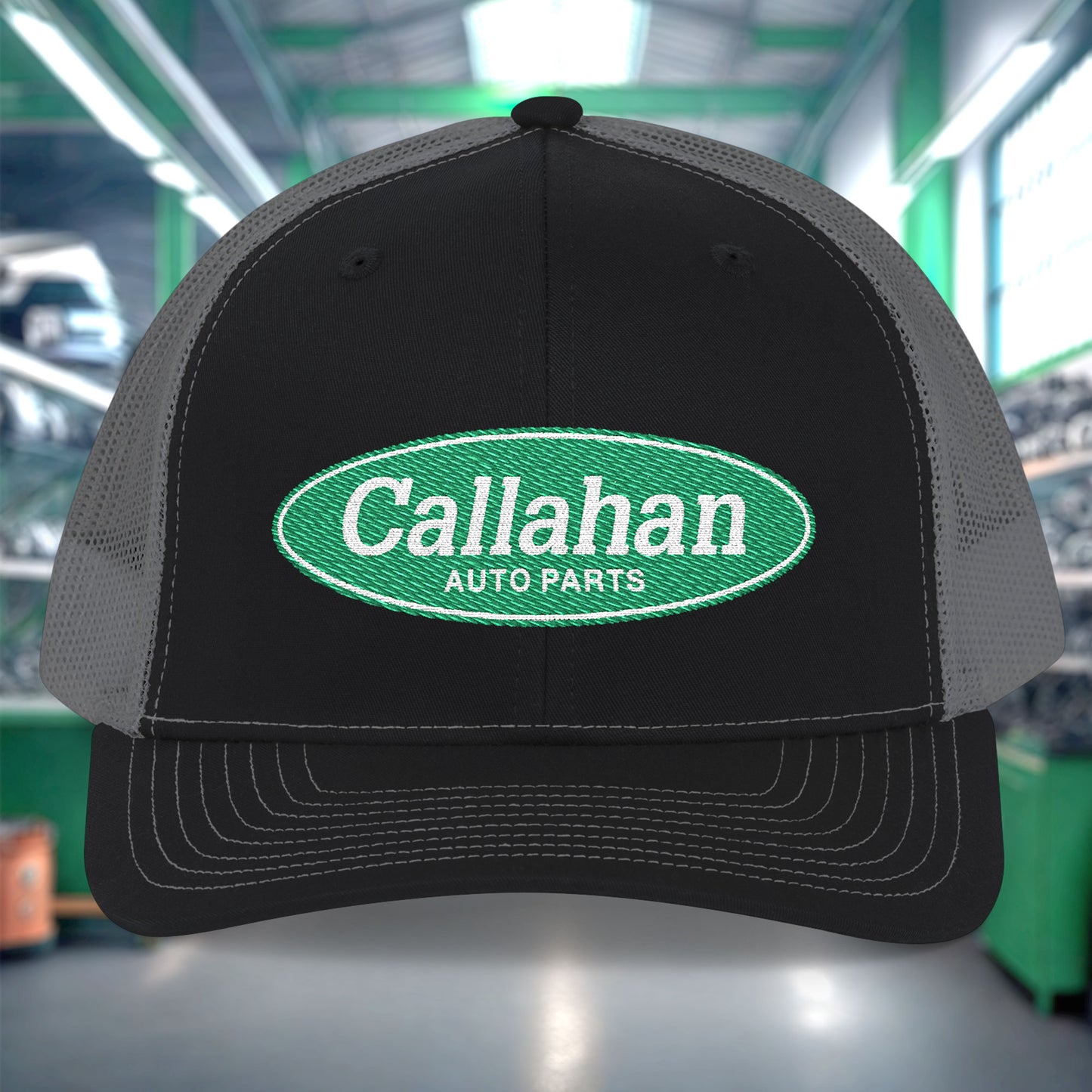 Black and gray cap with Callahan Auto Parts logo in a garage setting