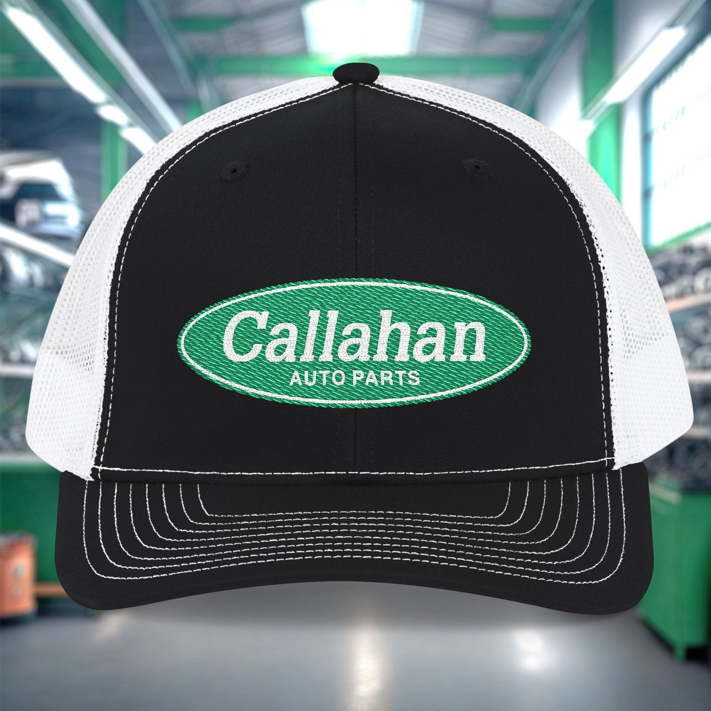 Black and white cap with Callahan Auto Parts logo in a garage setting