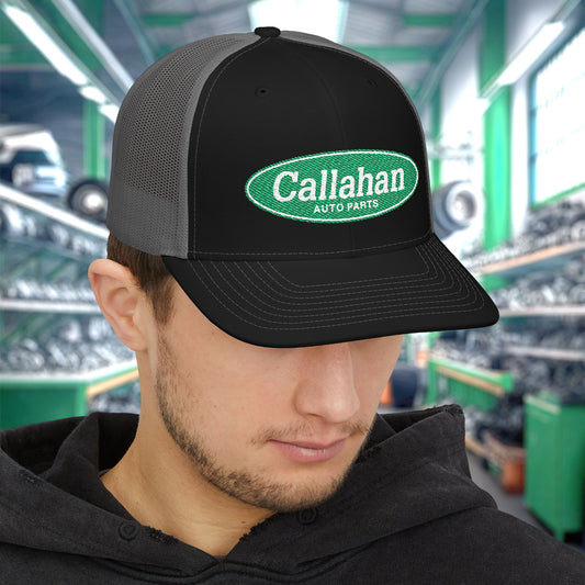 Man wearing Black and Charcoal Richardson 112 trucker cap with embroidered green Callahan Auto Parts logo inspired by Tommy Boy.