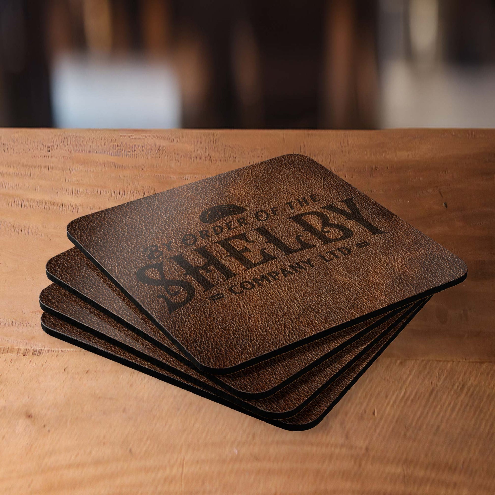 Set of 4 stacked corkwood drink coasters on a table with Shelby Company LTD logo from Peaky Blinders in vintage leather-style print.