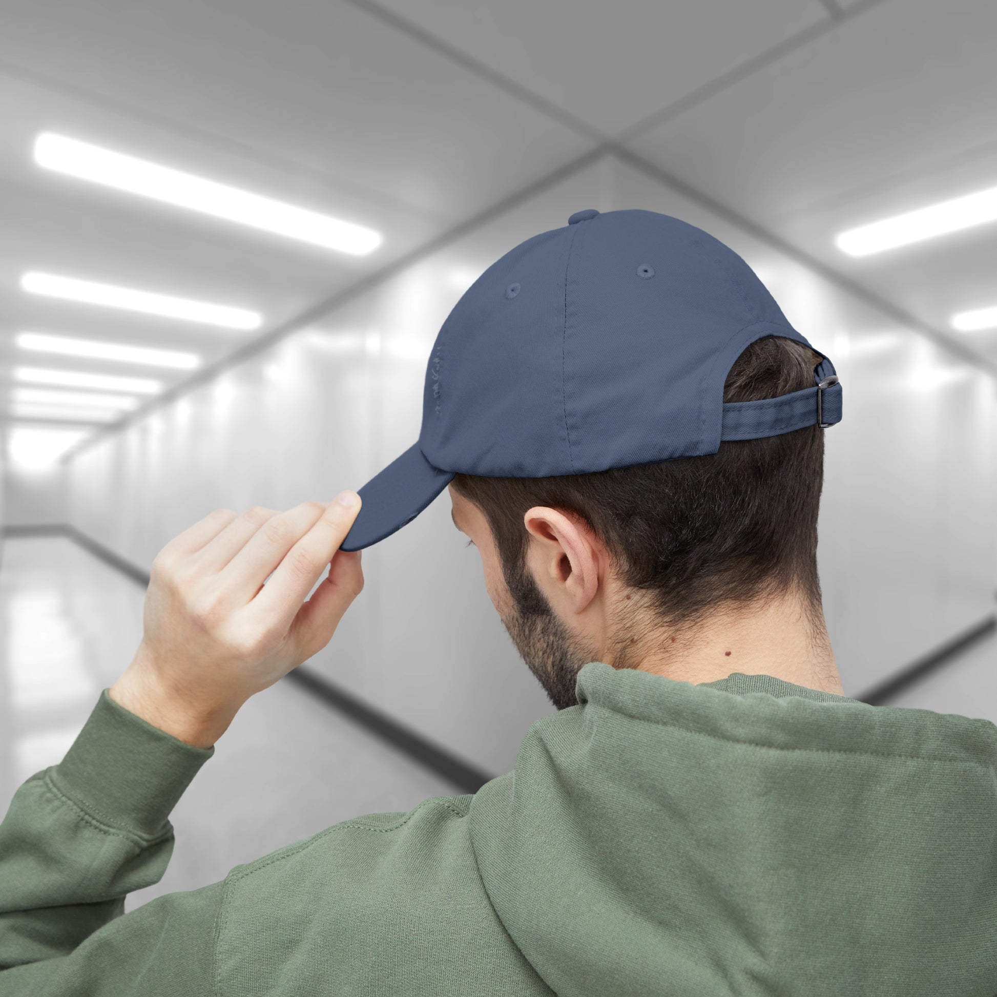 Back view of a male model wearing a Scotland blue District DT600 Vintage Distressed Baseball Cap with the Lumon Industries logo from the show Severance.