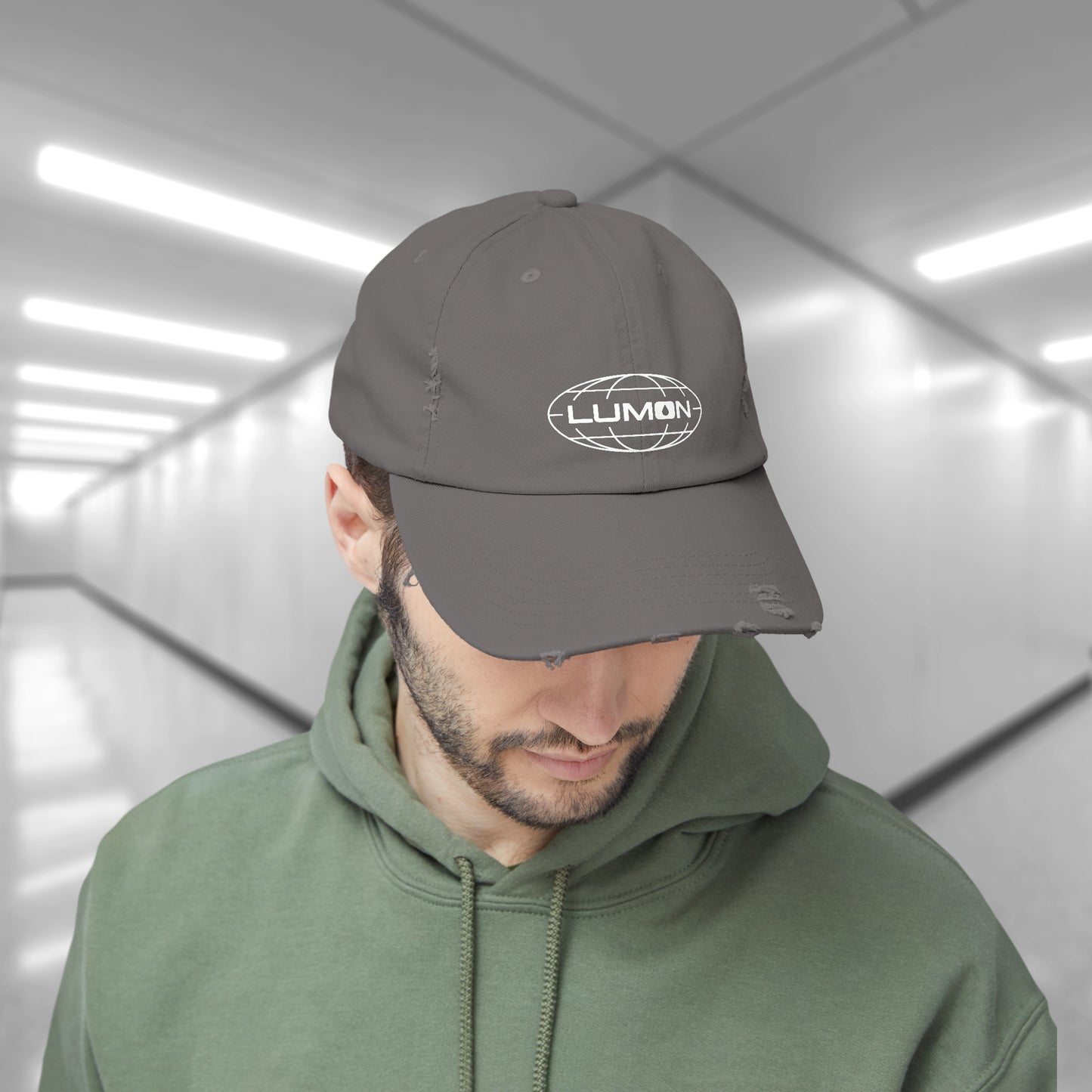 Male model wearing a nickel gray District DT600 Vintage Distressed Baseball Cap with the Lumon Industries logo from the show Severance.