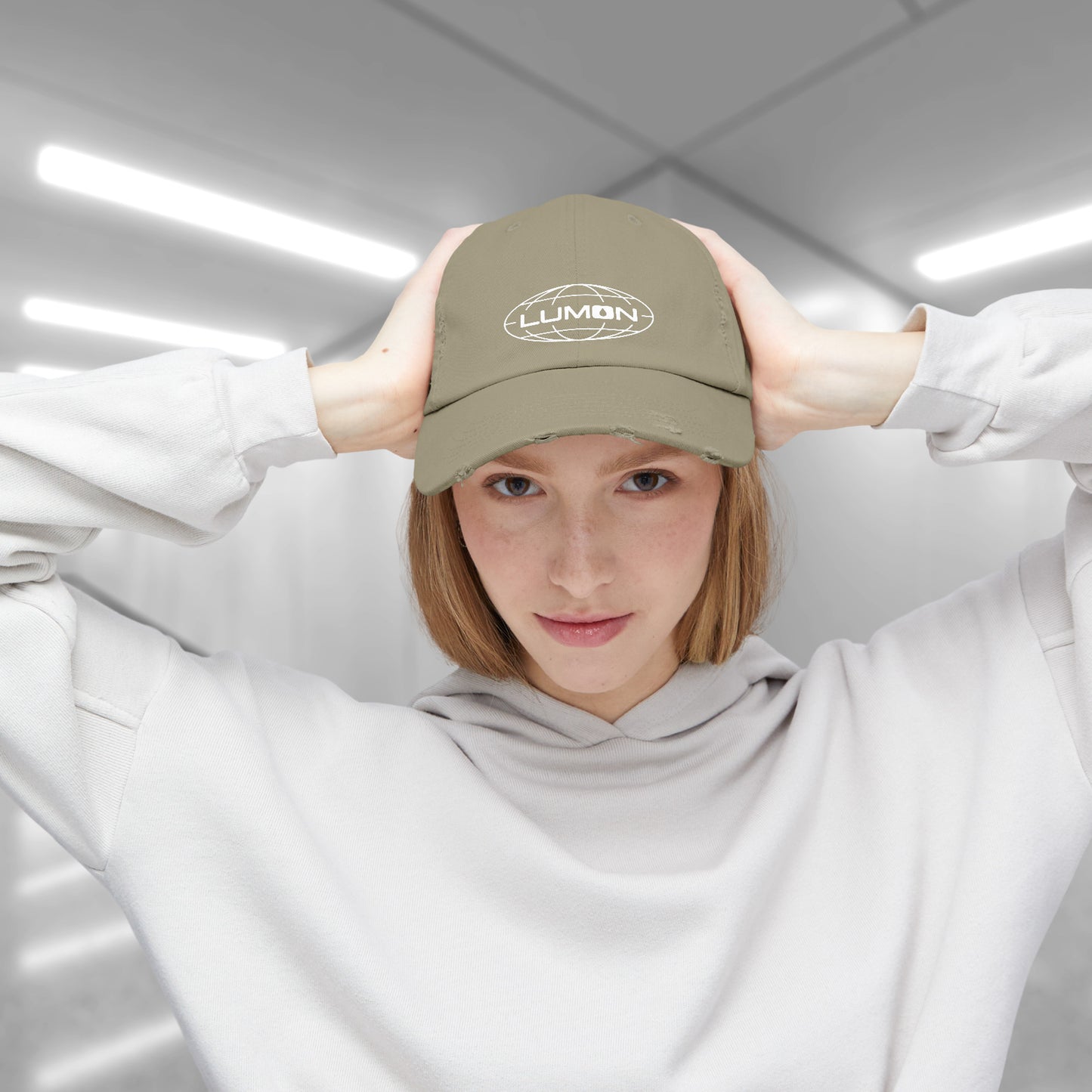 Female model wearing a Light Olive District DT600 Vintage Distressed Baseball Cap with the Lumon Industries logo from the show Severance.