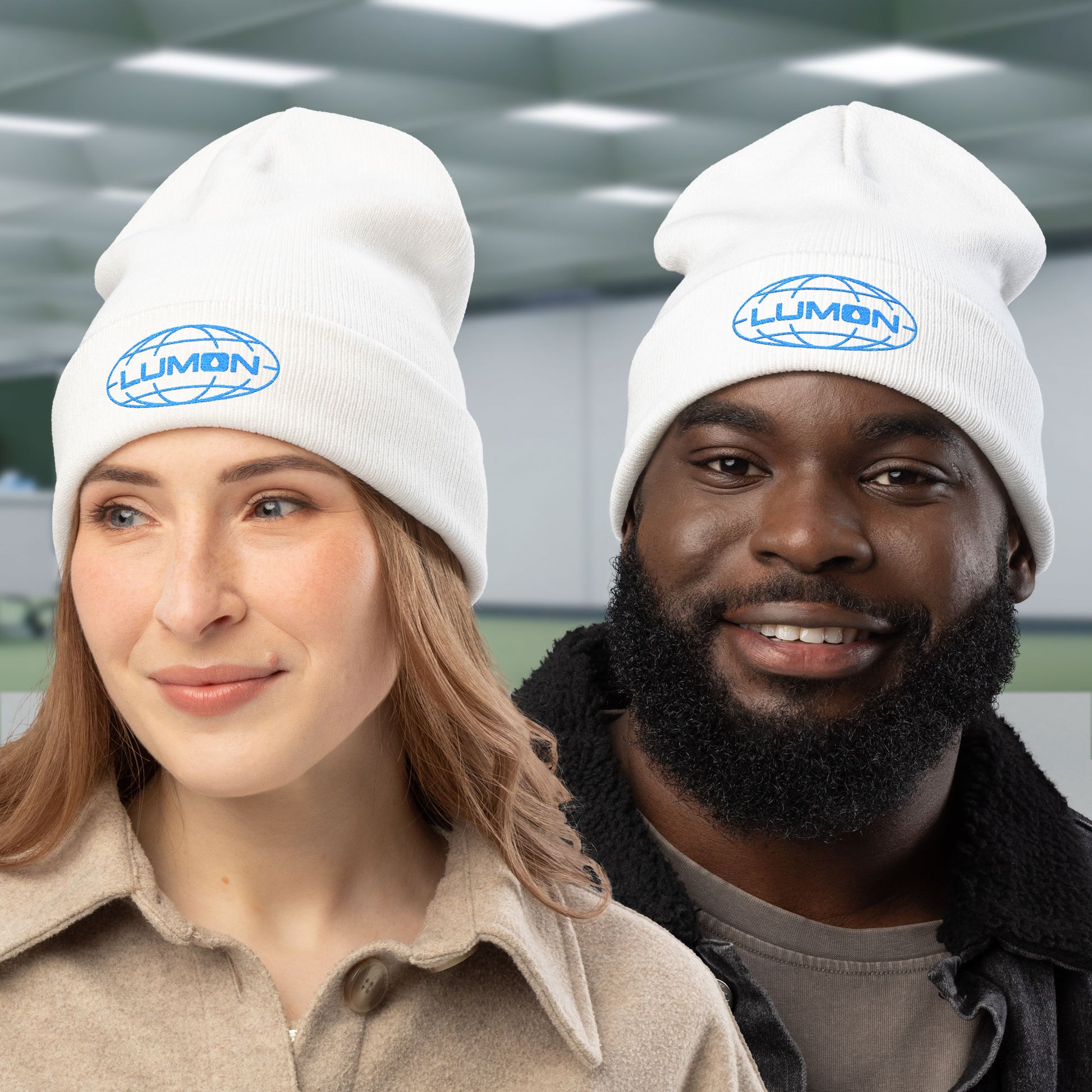 Two peeple wearing white knit beanies with embroidered blue Lumon Industries logo from Apple TV’s Severance.