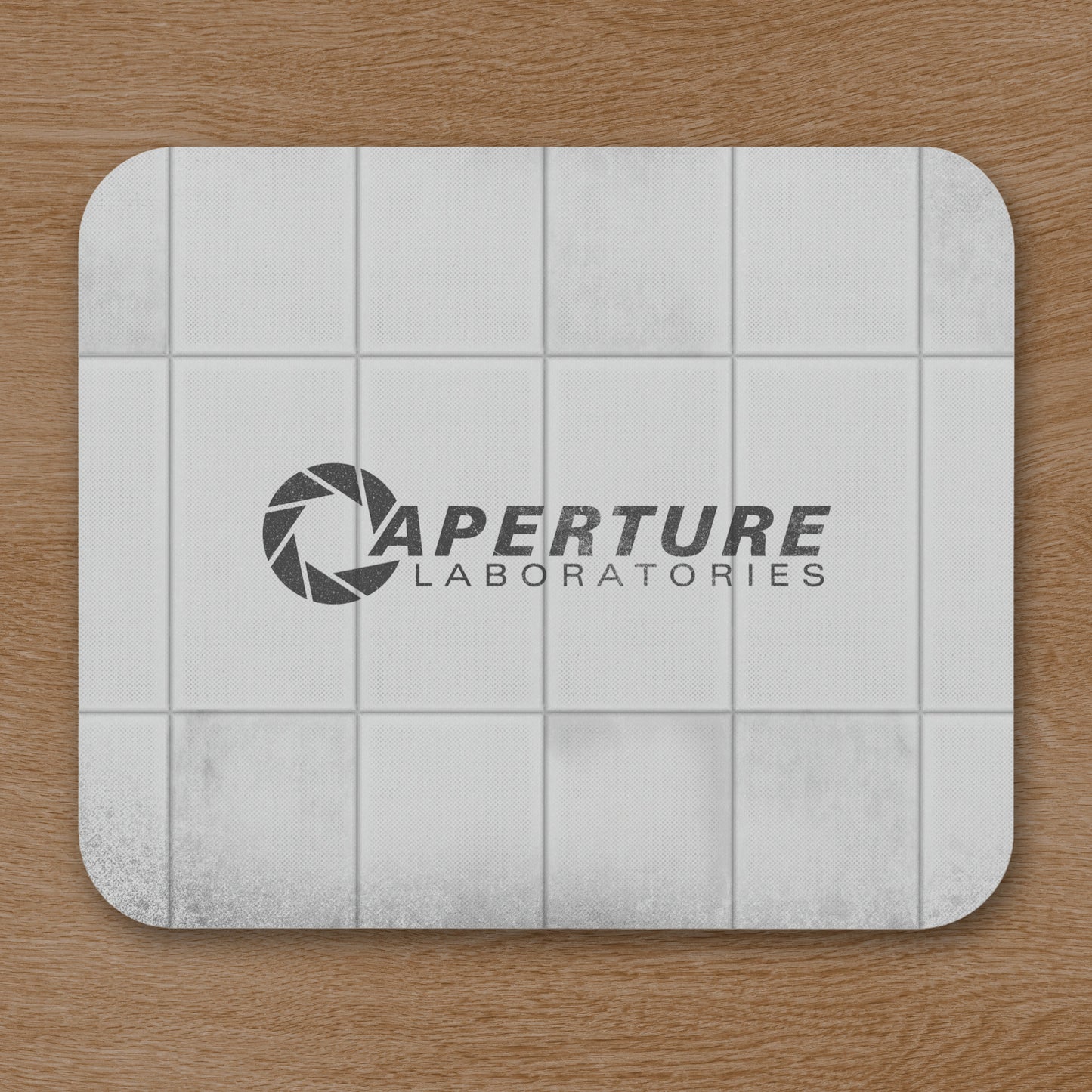 Mouse pad featuring Aperture Laboratories logo with a grungy panel wall texture design, shown on a desk.