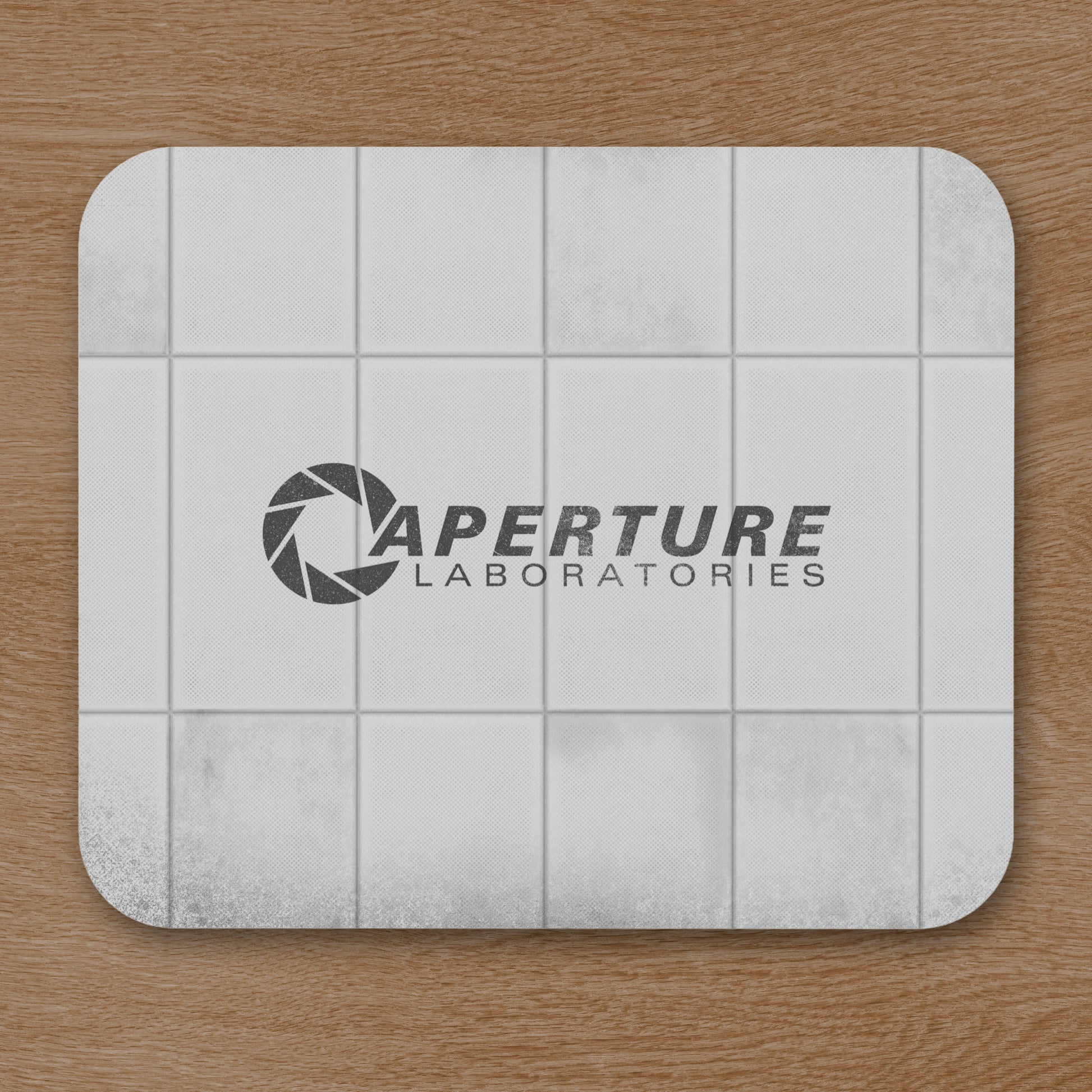 Mouse pad featuring Aperture Laboratories logo with a grungy panel wall texture design, shown on a desk.