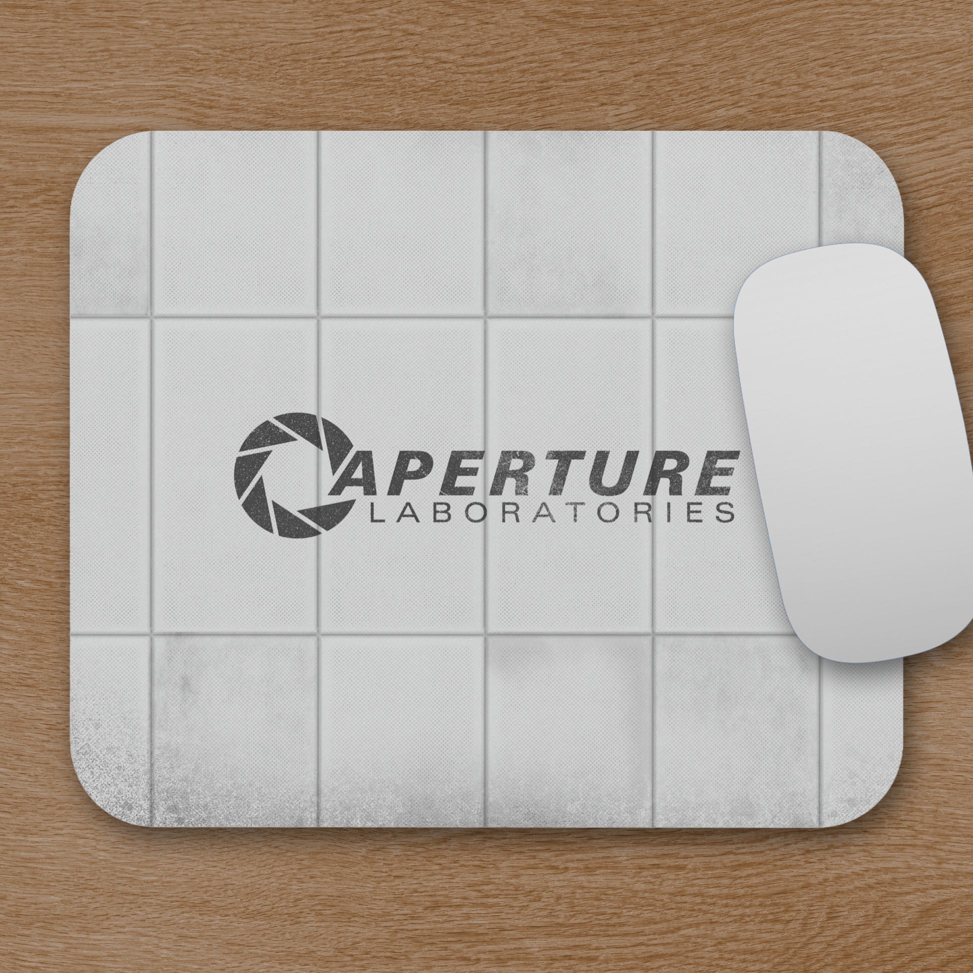 Mouse pad featuring Aperture Laboratories logo with a grungy panel wall texture design, shown with mouse on a desk.