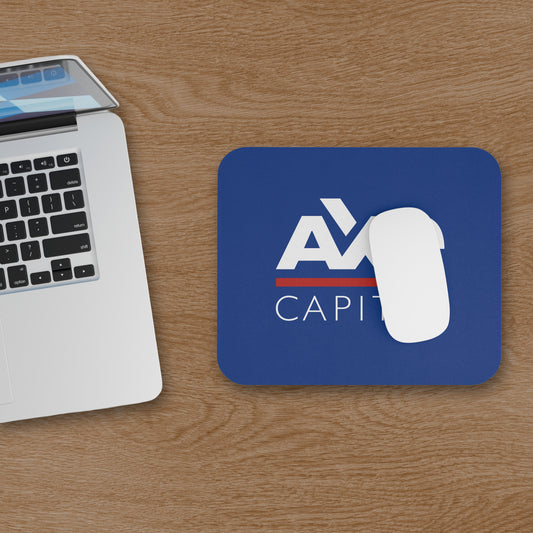 Topdown view of blue Axe Capital mouse pad inspired by the TV show Billions, shown with a mouse on a wooden desk next to a computer.