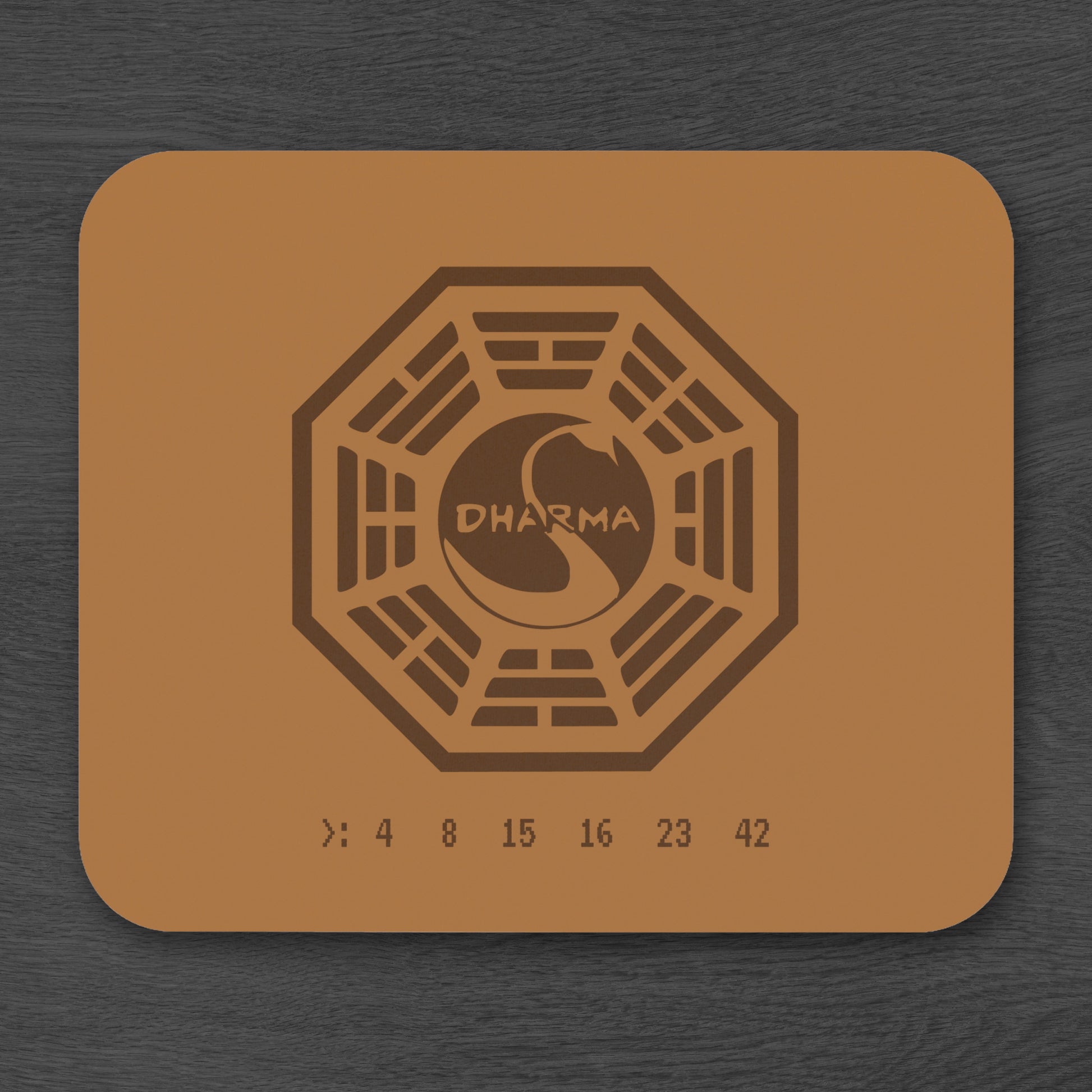 Topdown view of tan 9x8 mouse pad with Dharma Initiative Swan Station logo and hatch numbers from TV show Lost, on a desk
