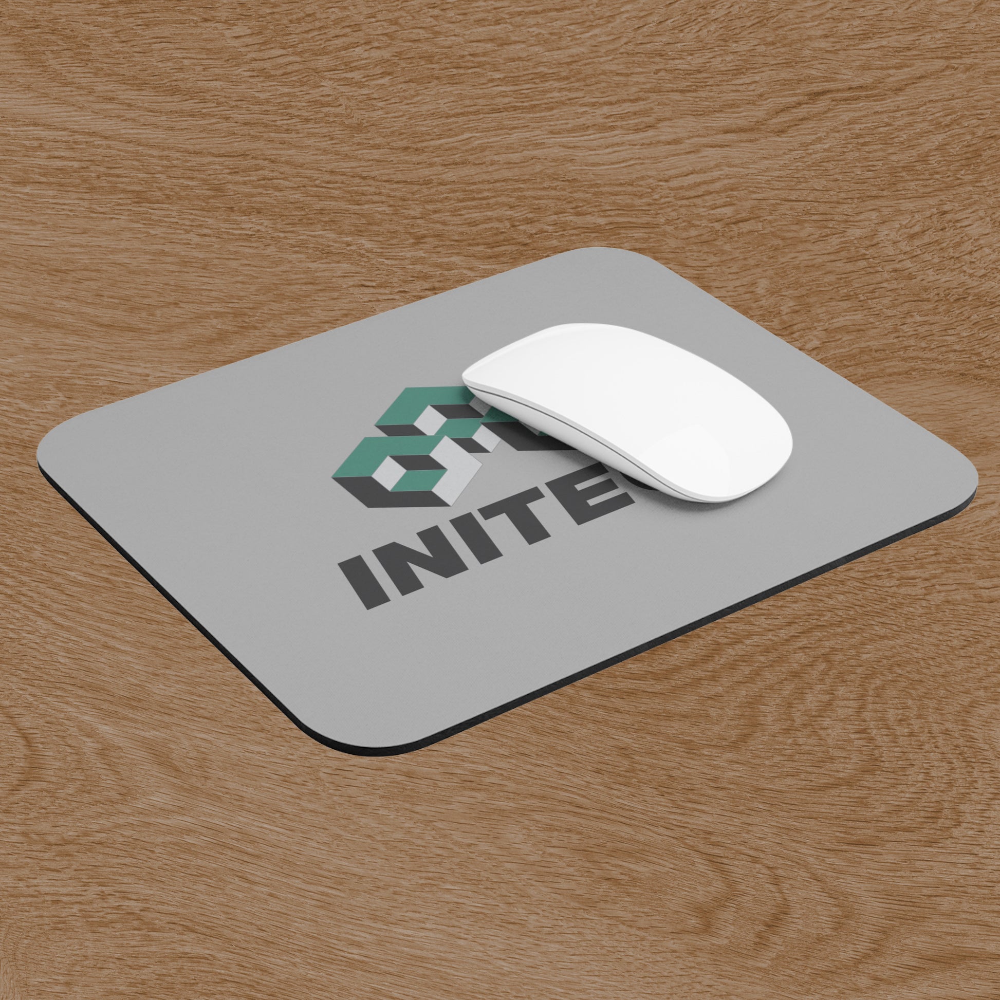 Angled view of Office Space Initech logo mouse pad on wooden desk, shown with a computer and mouse.