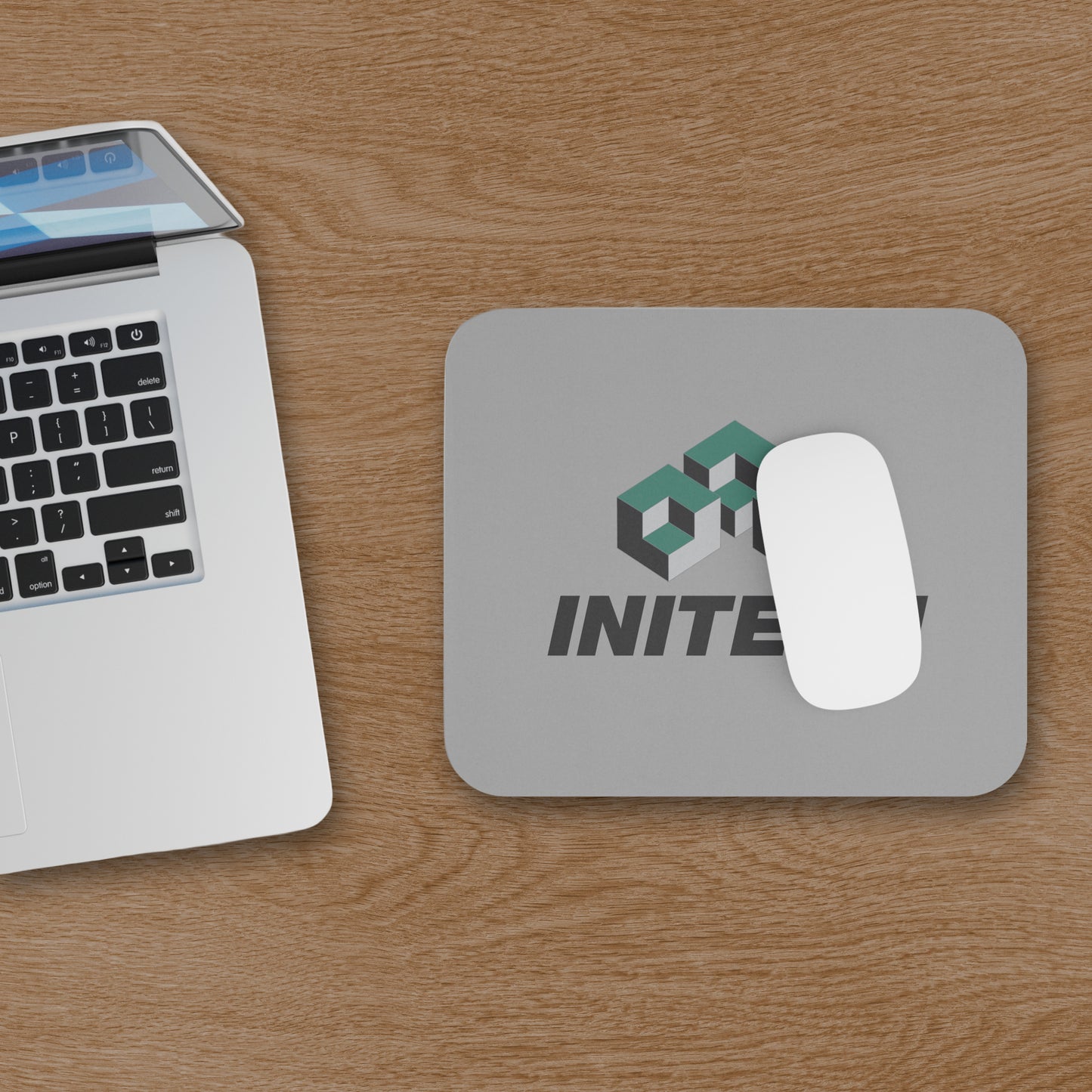 Office Space Initech logo mouse pad on wooden desk, shown with a computer and mouse.