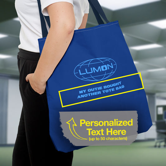 Female model carrying a 18" x 18" Blue Tote Bag featuring the logo of Lumon Industries from the Apple TV Show Severance, along with added customizable text by the customer, which is "MY OUTIE BOUGHT ANOTHER TOTE BAG."