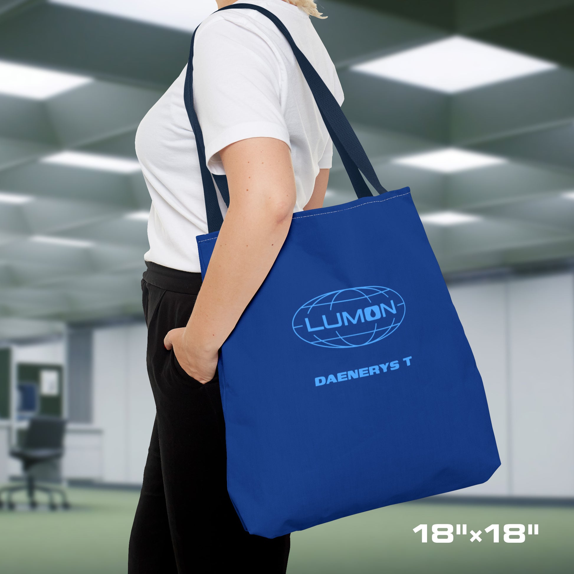 Female model carrying a 18" x 18" Blue Tote Bag featuring the logo of Lumon Industries from the Apple TV Show Severance, along with added customizable text by the customer, which is "DAENERYS T."