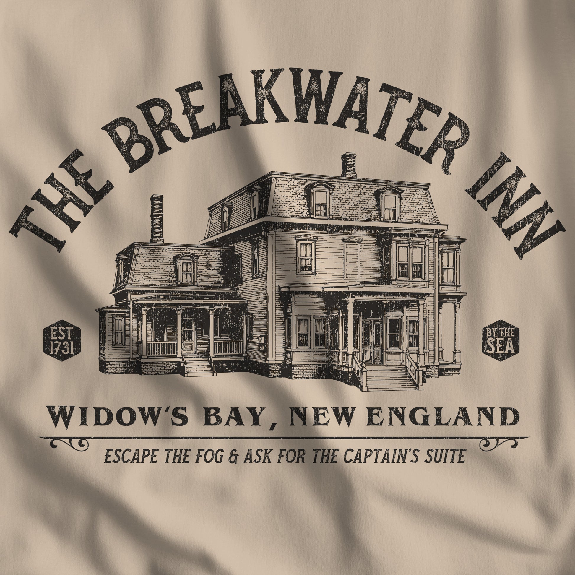 Closeup of 'The Breakwater Inn' vintage illustrated t-shirt inspired by Widow's Bay Apple TV series, soft Bella+Canvas cotton fan tee