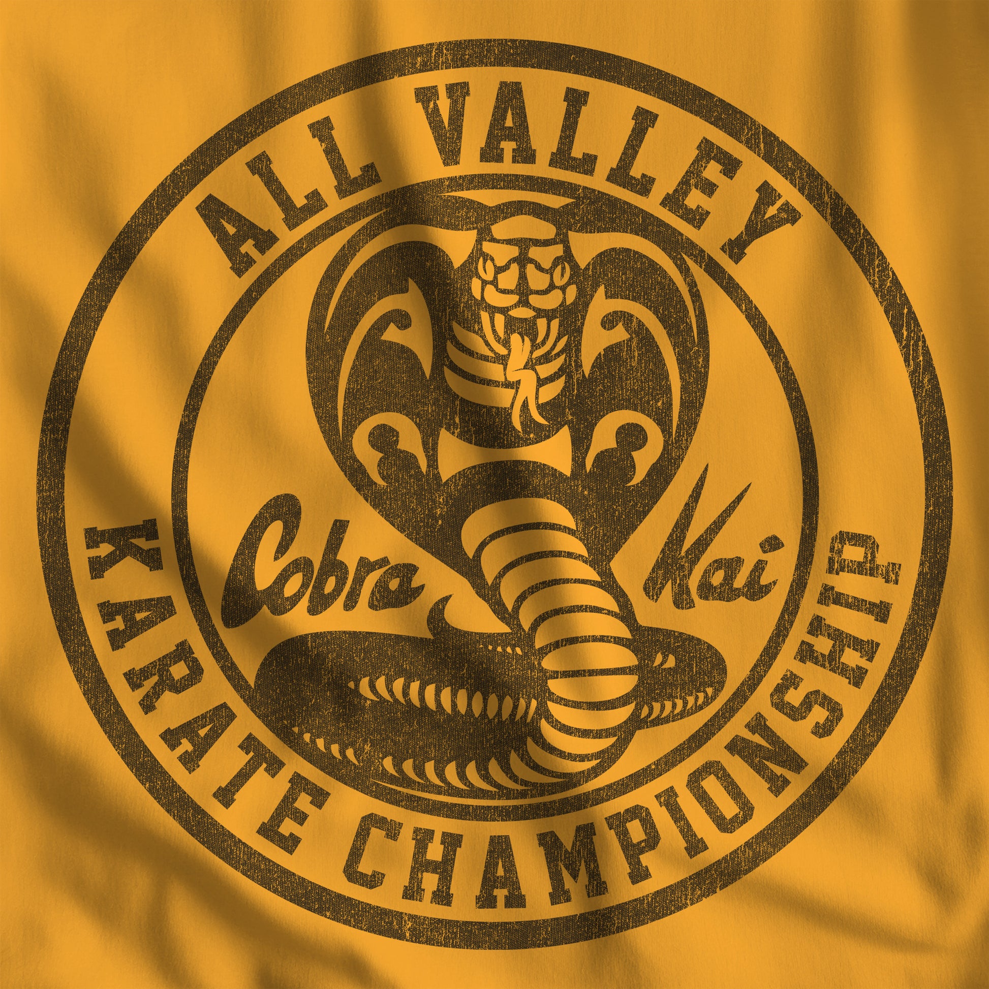 Closeup of Gold Cobra Kai All Valley Karate Championship vintage distressed graphic t-shirt, soft Bella+Canvas cotton Karate Kid tee