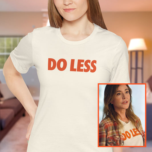Woman wearing Off-white Natural colored 'Do Less' graphic t-shirt inspired by Shrinking TV show, Bella+Canvas cotton tee with orange type