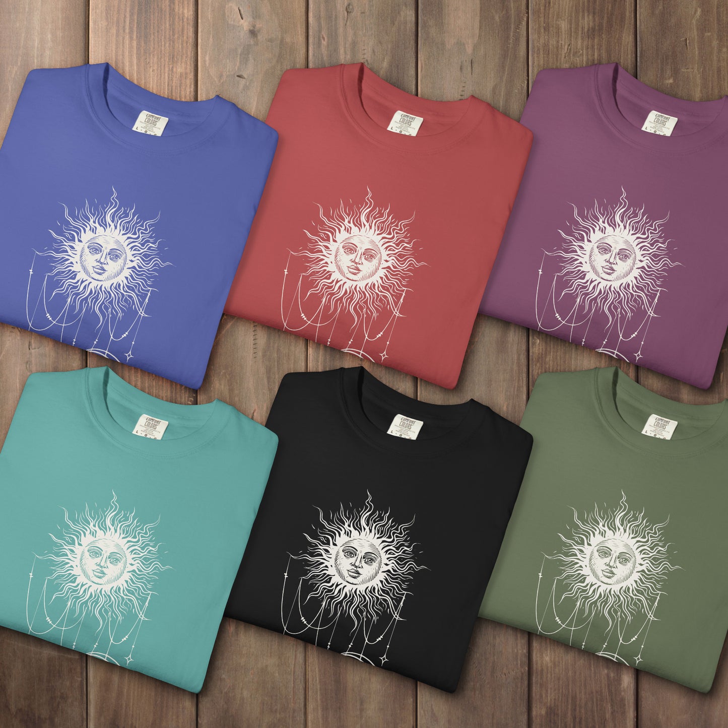 Six folded Comfort Colors tees with a celestial sun and crescent moon design, worn by Patricia in Widow's Bay S1E8