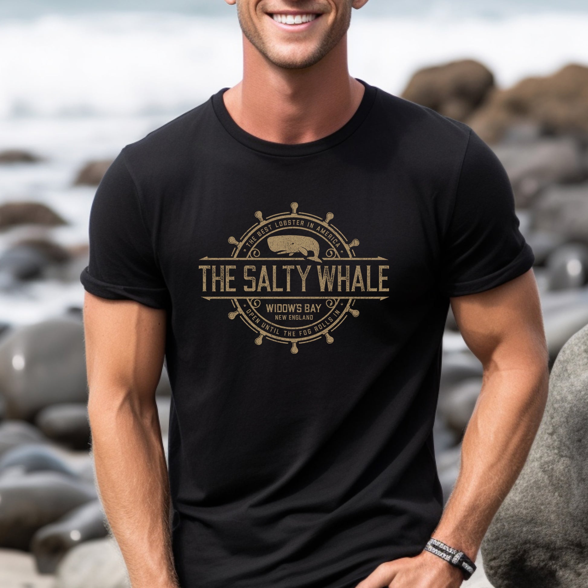 Man wearing black The Salty Whale vintage distressed pub logo t-shirt inspired by Widow's Bay Apple TV series, soft Bella+Canvas cotton tee