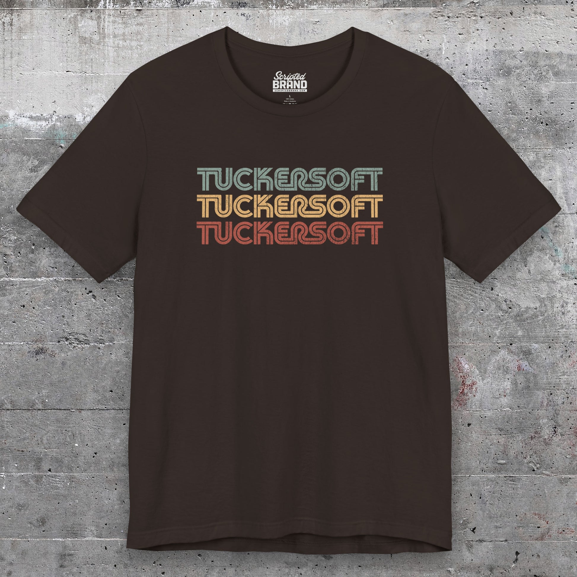 Front view of a brown soft Bella+Canvas 3001 short-sleeve t-shirt tee featuring a logo graphic of the 1980s fictional video game company Tuckersoft inspired by the TV show Black Mirror and the episode Bandersnatch in a vintage distressed style, sold by ScriptedBrand.