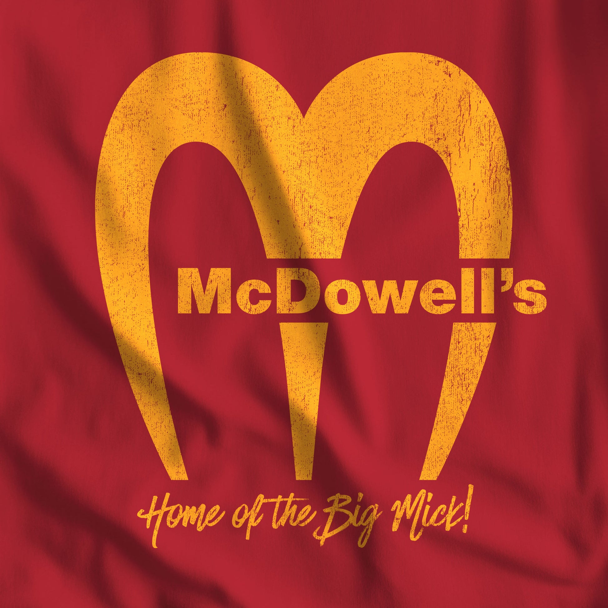 Closeup of Red Bella+Canvas t-shirt featuring the McDowells logo from the movie Coming to America in a vintage distressed style.