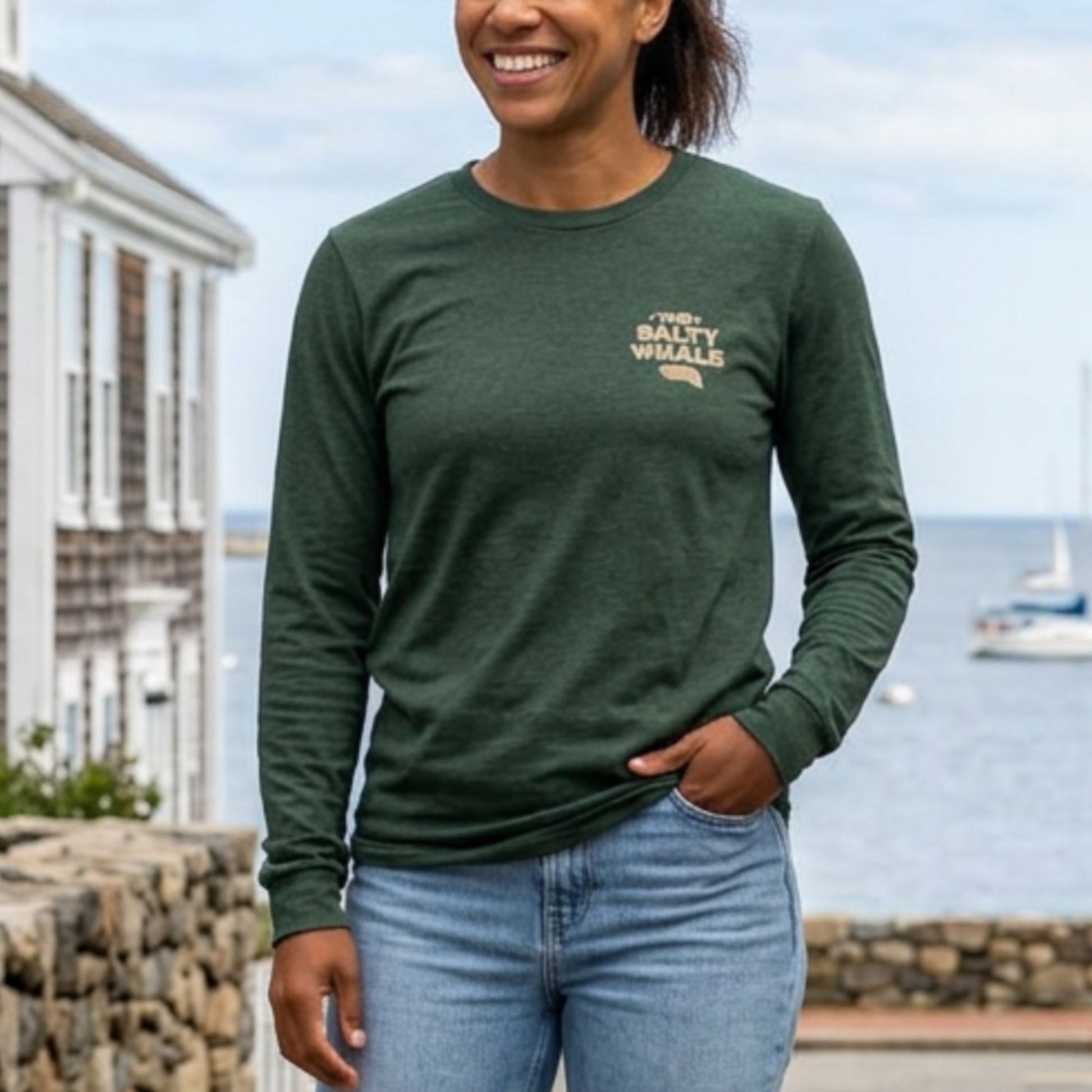 Front of person wearing Heather forest green long sleeve tee with vintage gold The Salty Whale logos from the TV show Widow's Bay nautical on front and back