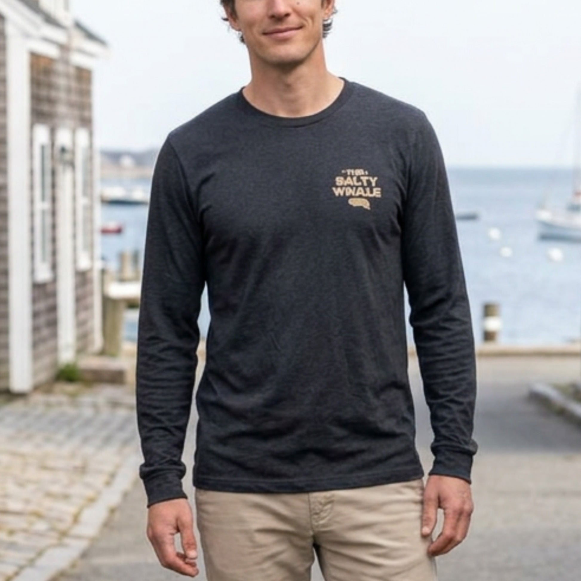 Front of person wearing Heather navy long sleeve tee with vintage gold The Salty Whale logos from the TV show Widow's Bay nautical on front and back