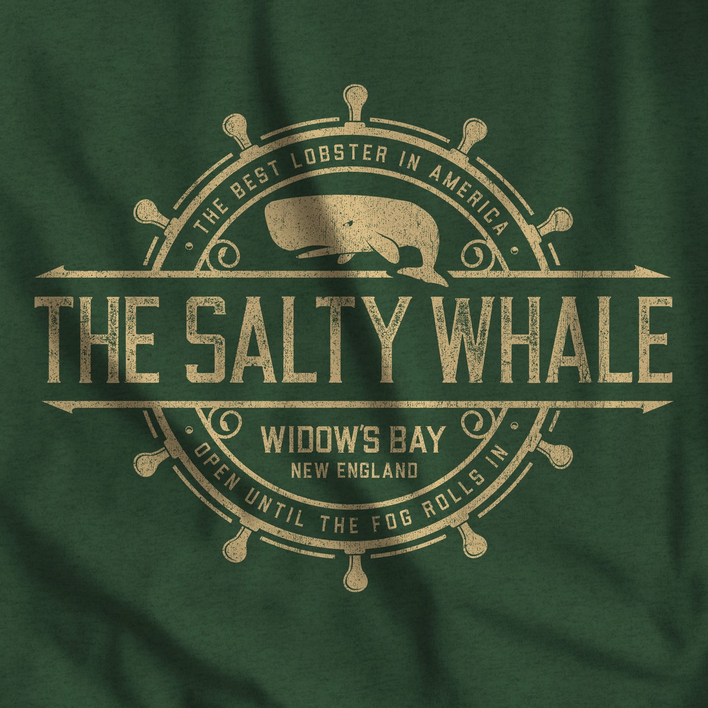 Closeup of Heather green long-sleeve tee with the gold distressed Salty Whale maritime crest logo from Widow's Bay, New England