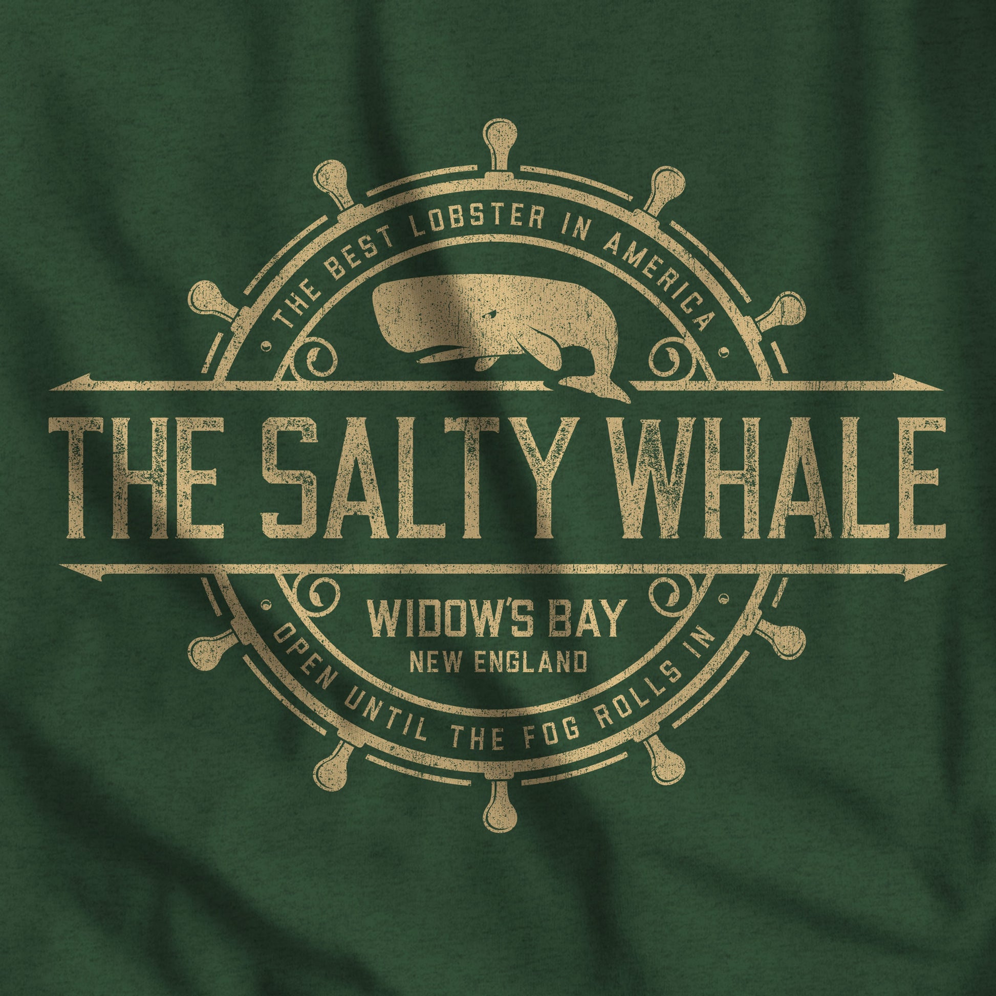Closeup of Heather green long-sleeve tee with the gold distressed Salty Whale maritime crest logo from Widow's Bay, New England