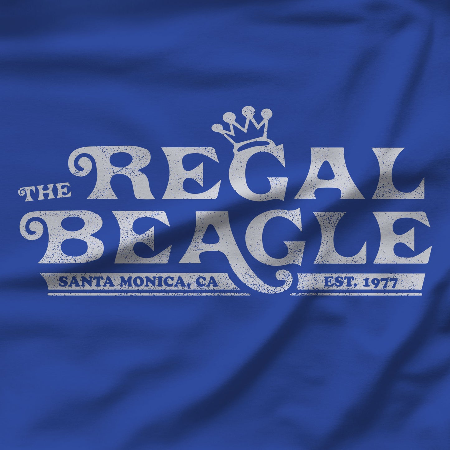 Closeup of royal blue womens boyfriend tee with vintage distressed Regal Beagle Three's Company logo