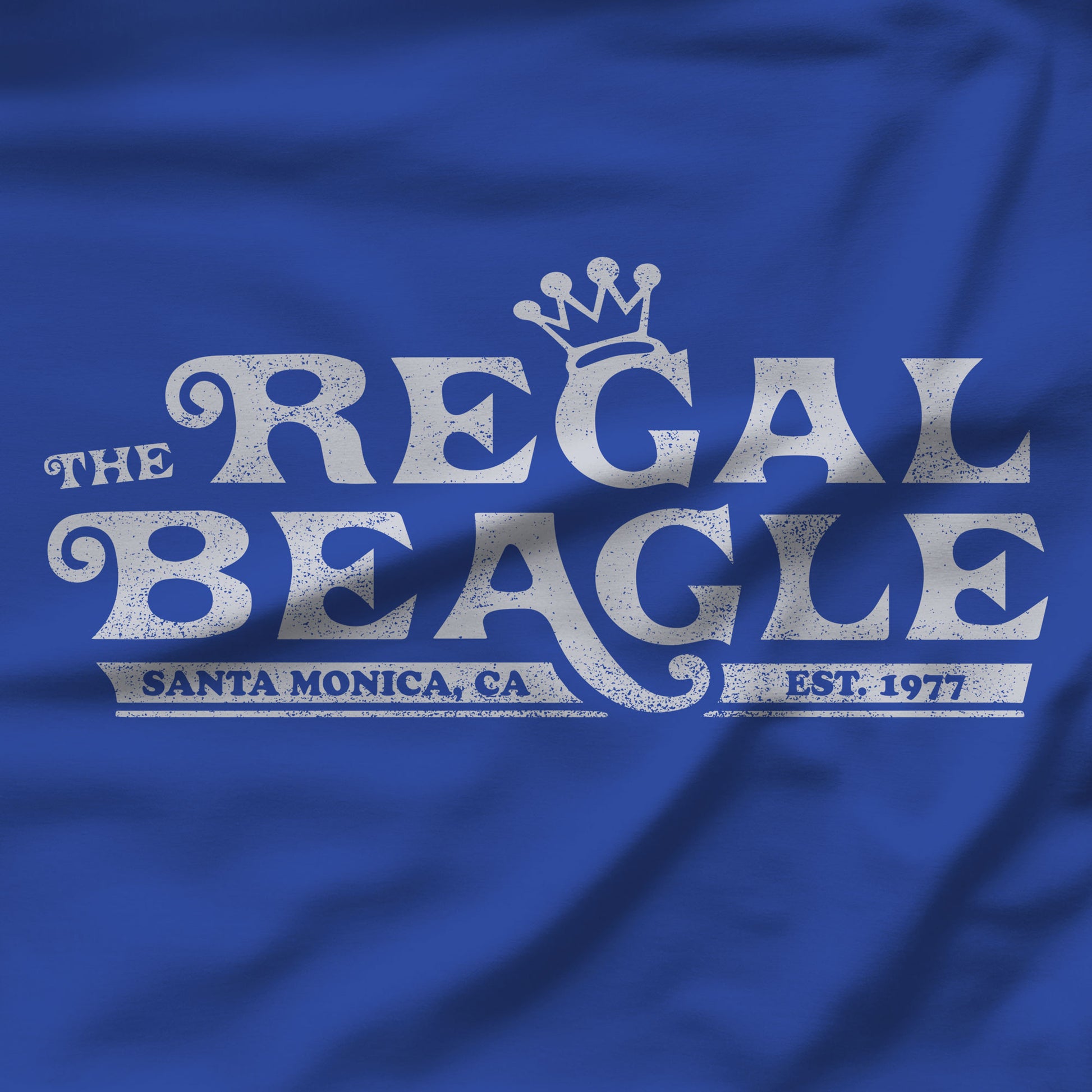 Closeup of royal blue womens boyfriend tee with vintage distressed Regal Beagle Three's Company logo