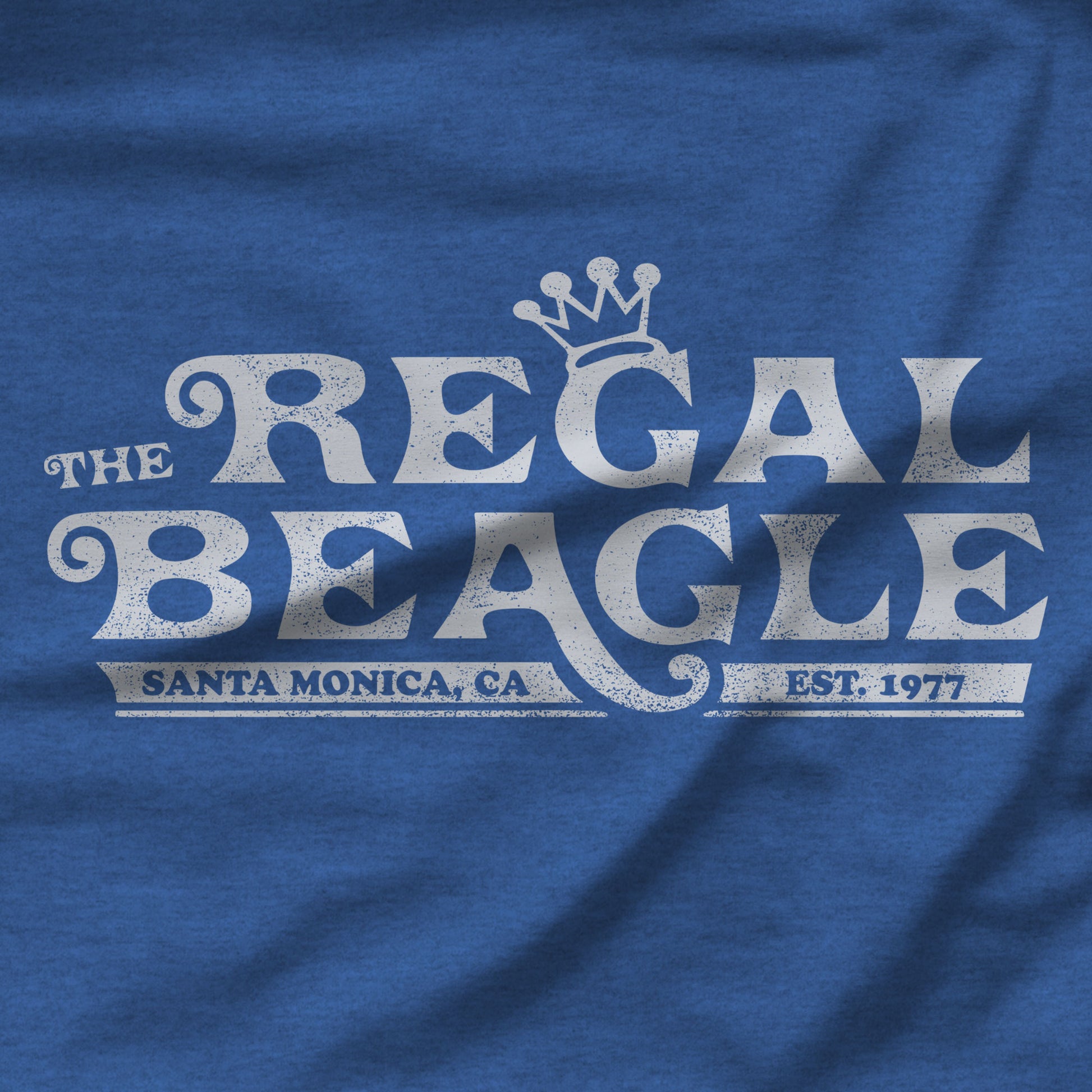 Closeup of Heather royal blue womens v-neck tee with vintage distressed Regal Beagle Three's Company logo