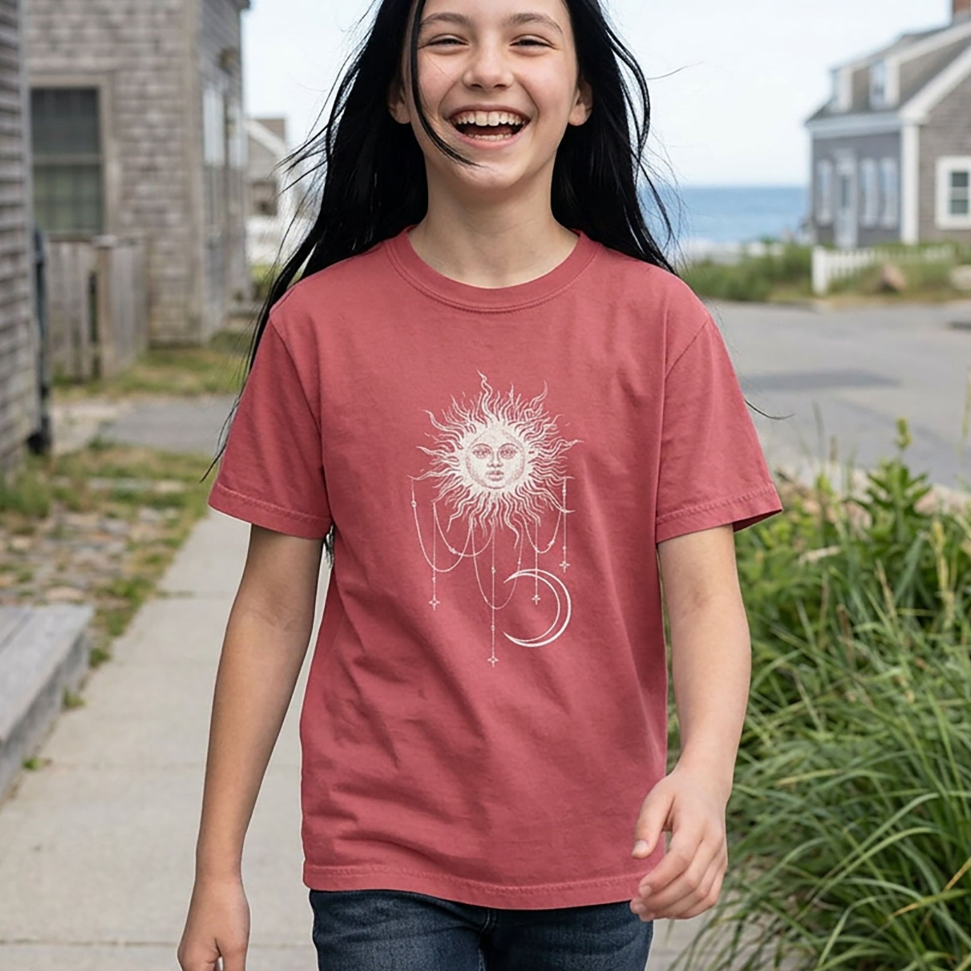 Crimson youth tee with Patricia boho celestial sun, stars, and crescent moon design from Widow's Bay worn by a girl