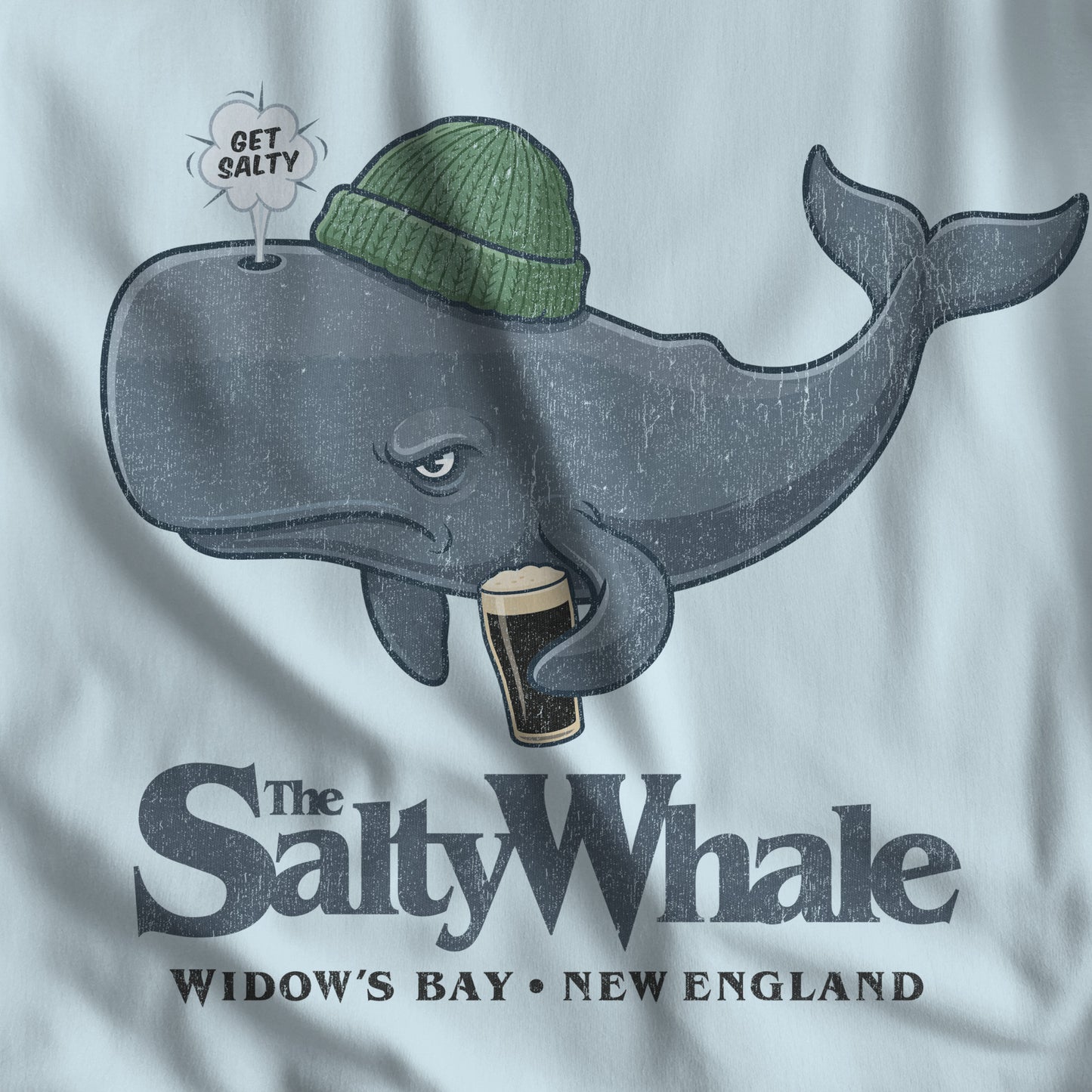 Closeup light blue Comfort Colors tank with the Salty Whale logo from Widow's Bay, a beanie-wearing cartoon whale drinking dark beer