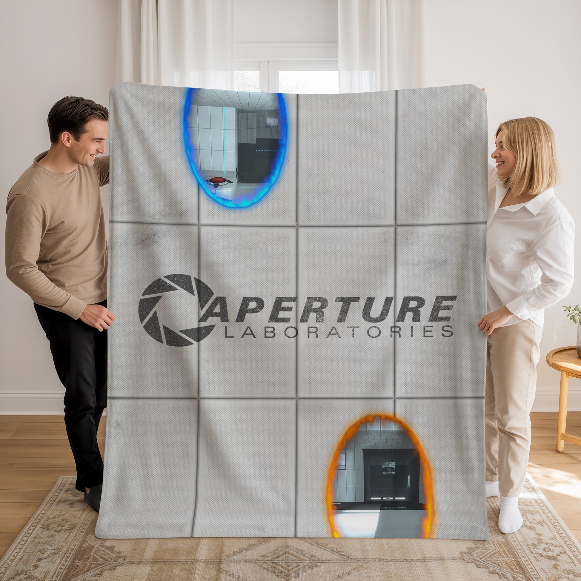 Man and woman holding up a Velveteen plush blanket with Portal 2 panel wall, Aperture Laboratories logo, and blue and orange portals.