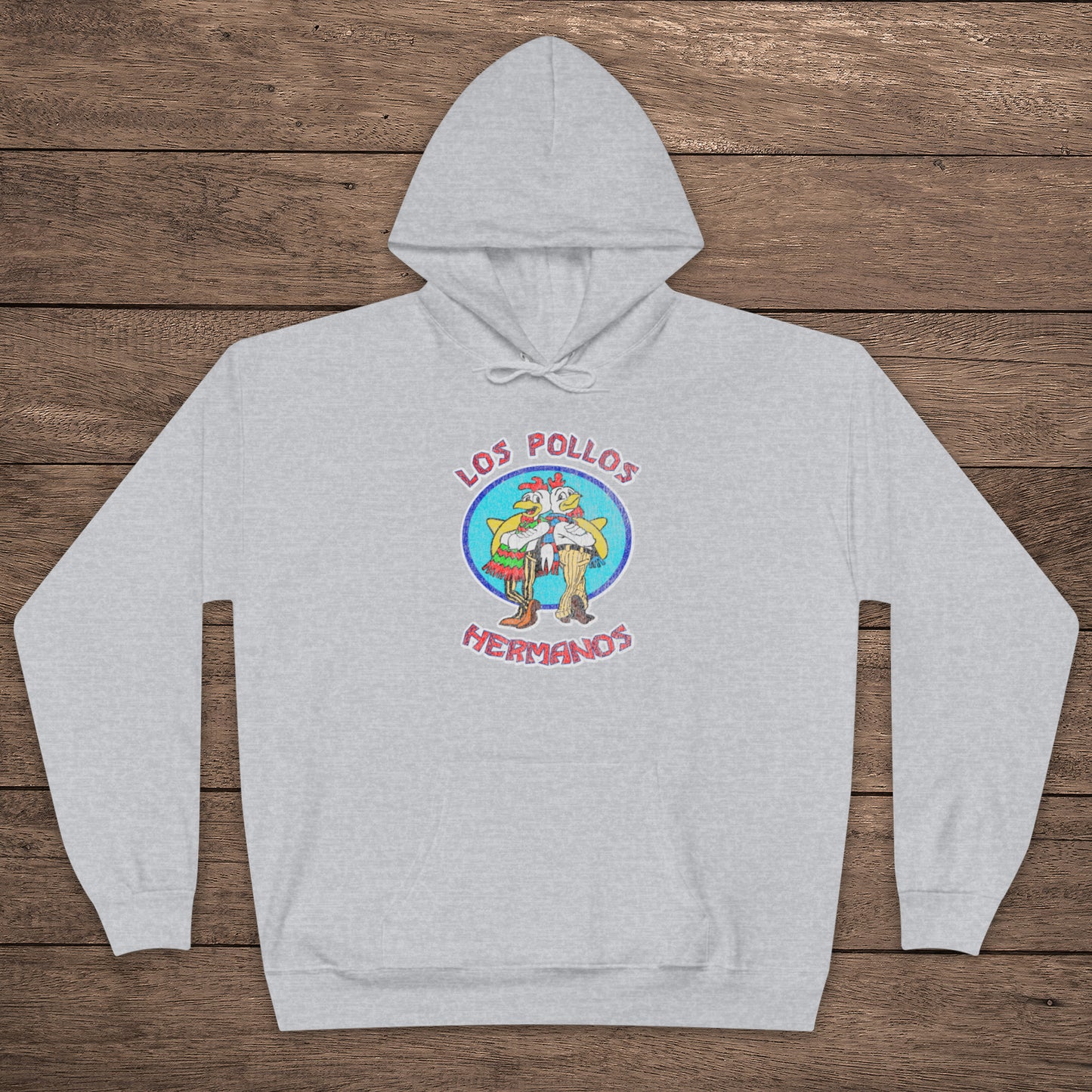 ash gray pullover hoodie with vintage distressed Los Pollos Hermanos logo from Breaking Bad on chest, shown on a wood floor.