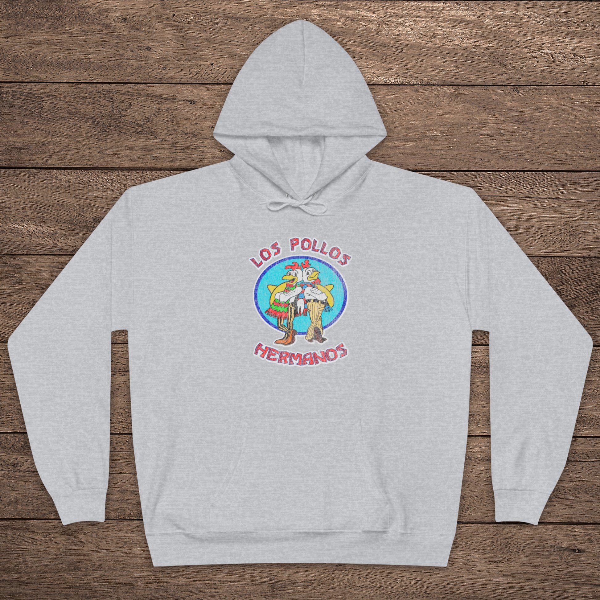 ash gray pullover hoodie with vintage distressed Los Pollos Hermanos logo from Breaking Bad on chest, shown on a wood floor.