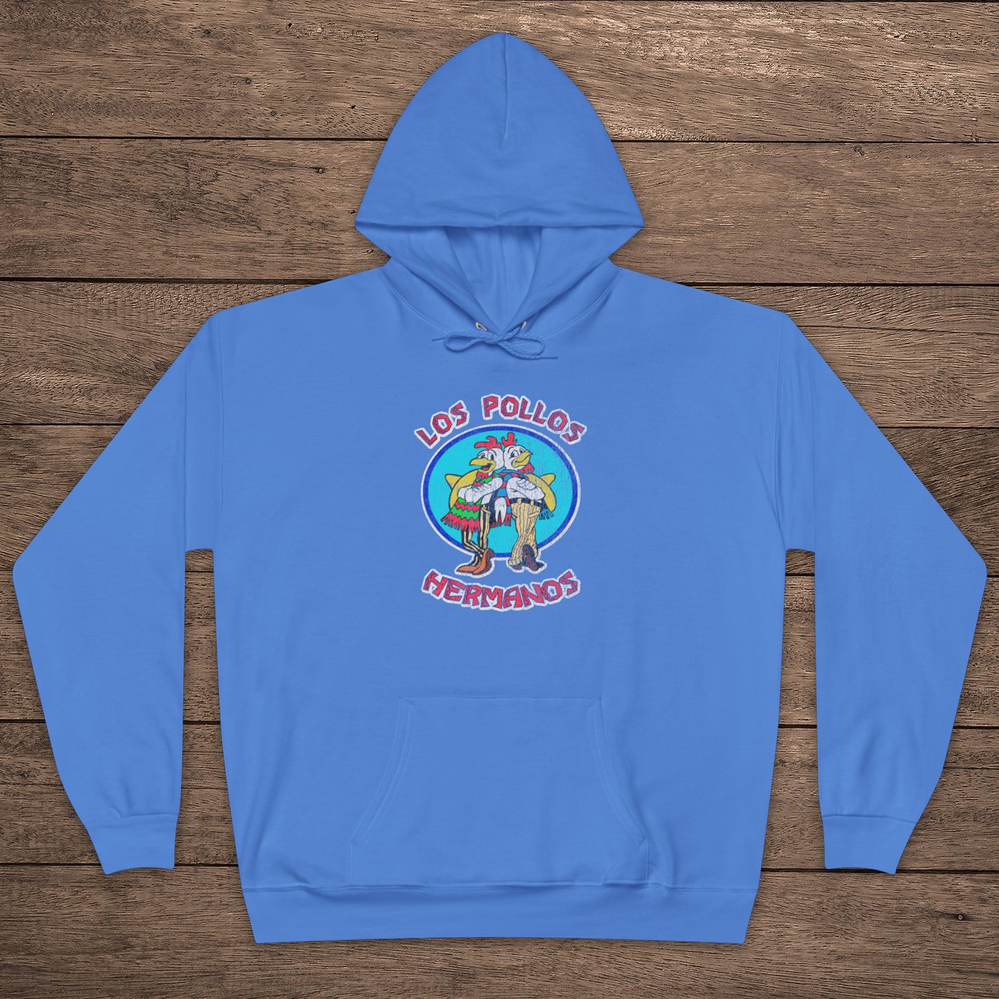 Carolina blue pullover hoodie with vintage distressed Los Pollos Hermanos logo from Breaking Bad on chest, shown on a wood floor.