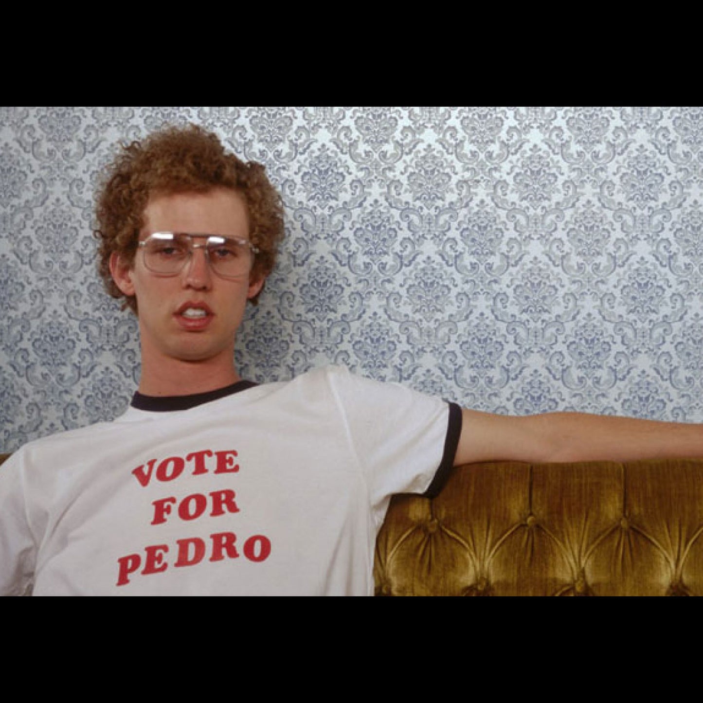 Napoleon Dynamite wearing white ringer tee with black trim and red custom text, shown as “VOTE FOR PEDRO”