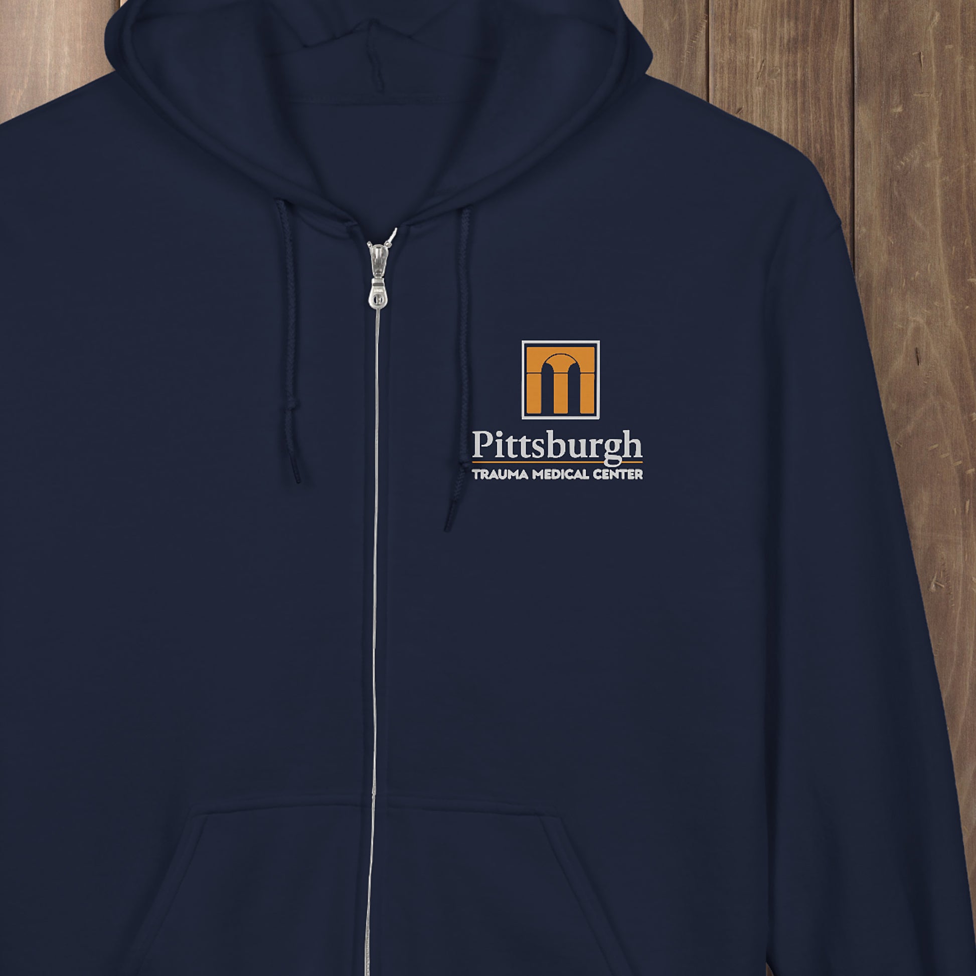 The Pitt hoodie featuring the Pittsburgh Trauma Medical Center logo. Cozy Gildan full-zip in 4 colors. Staff-style gear for fans of the ER drama.