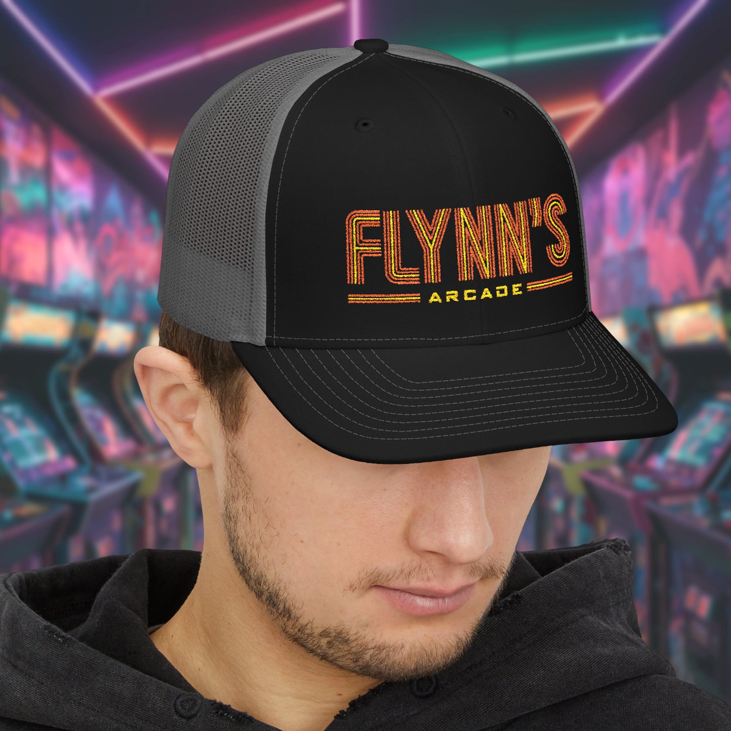 Man wearing Black and charcoal Richardson 112 snapback trucker cap with 'Flynn’s Arcade' neon logo inspired by TRON.