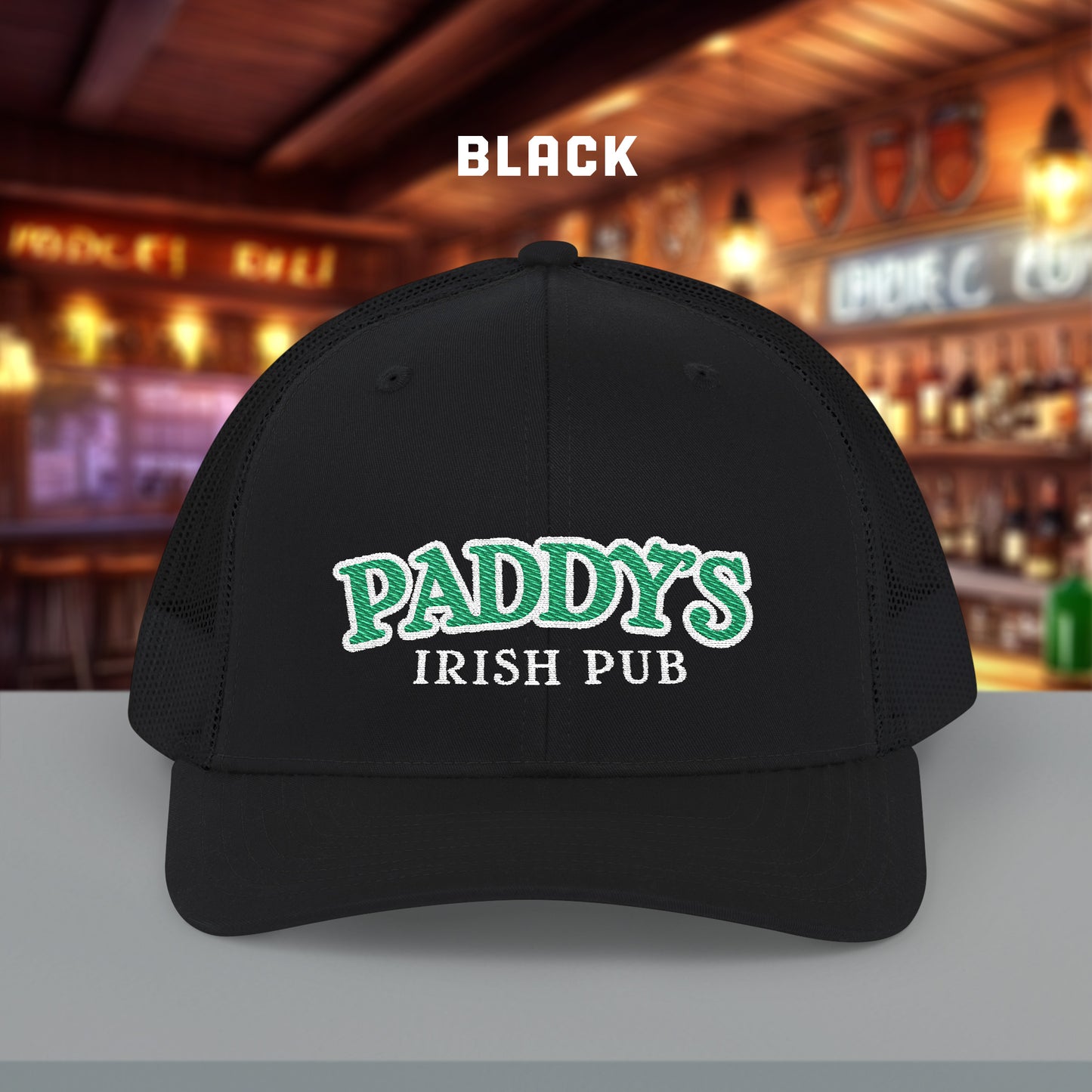 All Black charcoal Richardson 112 trucker cap with green Paddy’s Irish Pub embroidered logo shown in a bar.