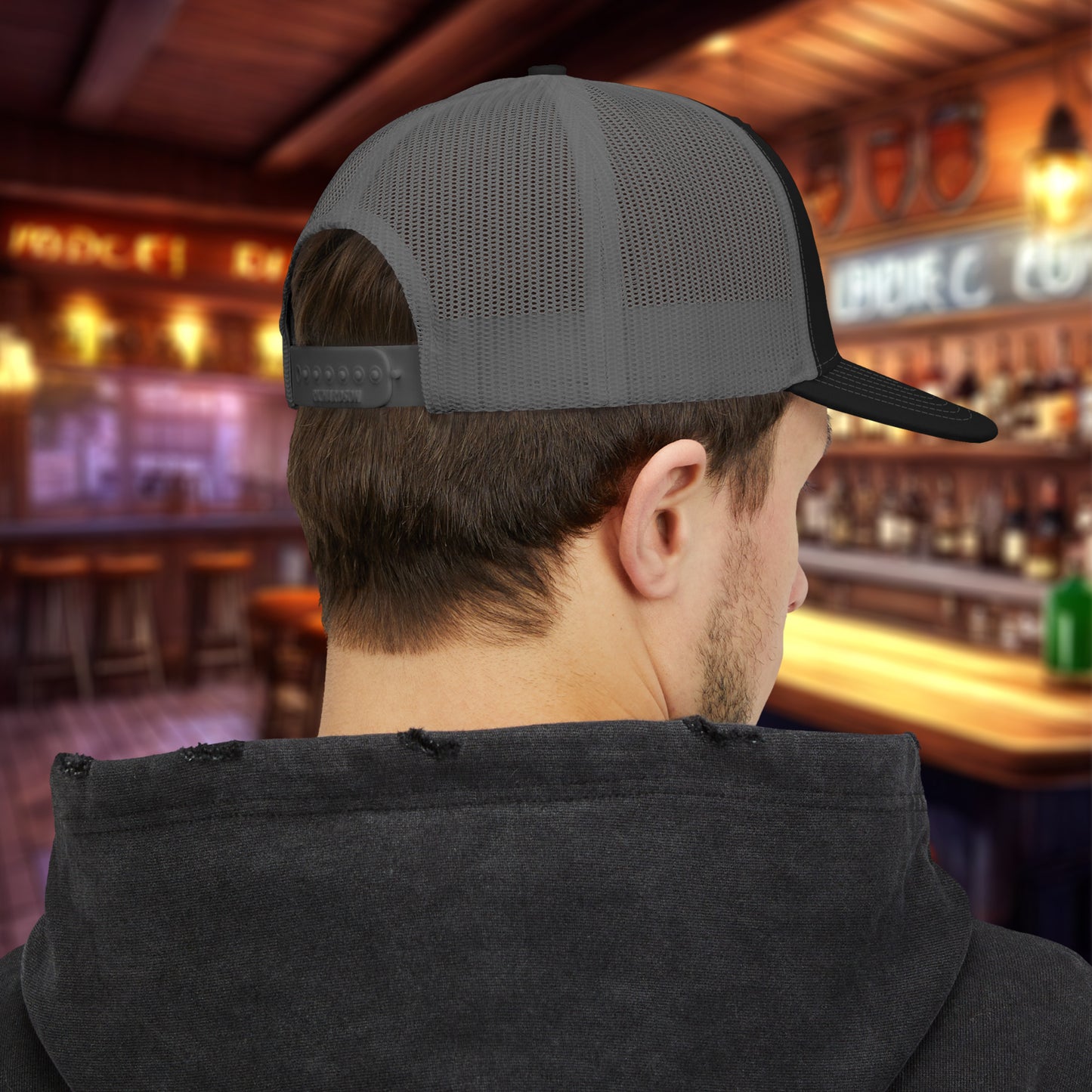 Rear view of man wearing Black charcoal Richardson 112 trucker cap with green Paddy’s Irish Pub embroidered logo in a bar.