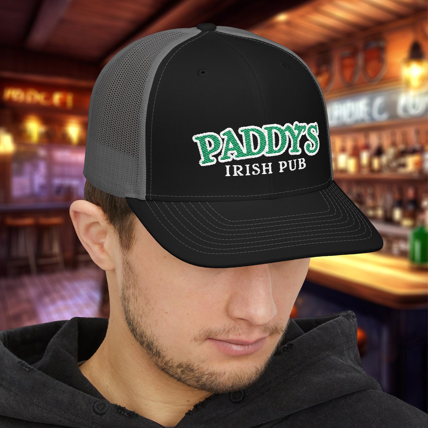 Man wearing Black charcoal Richardson 112 trucker cap with green Paddy’s Irish Pub embroidered logo in a bar.