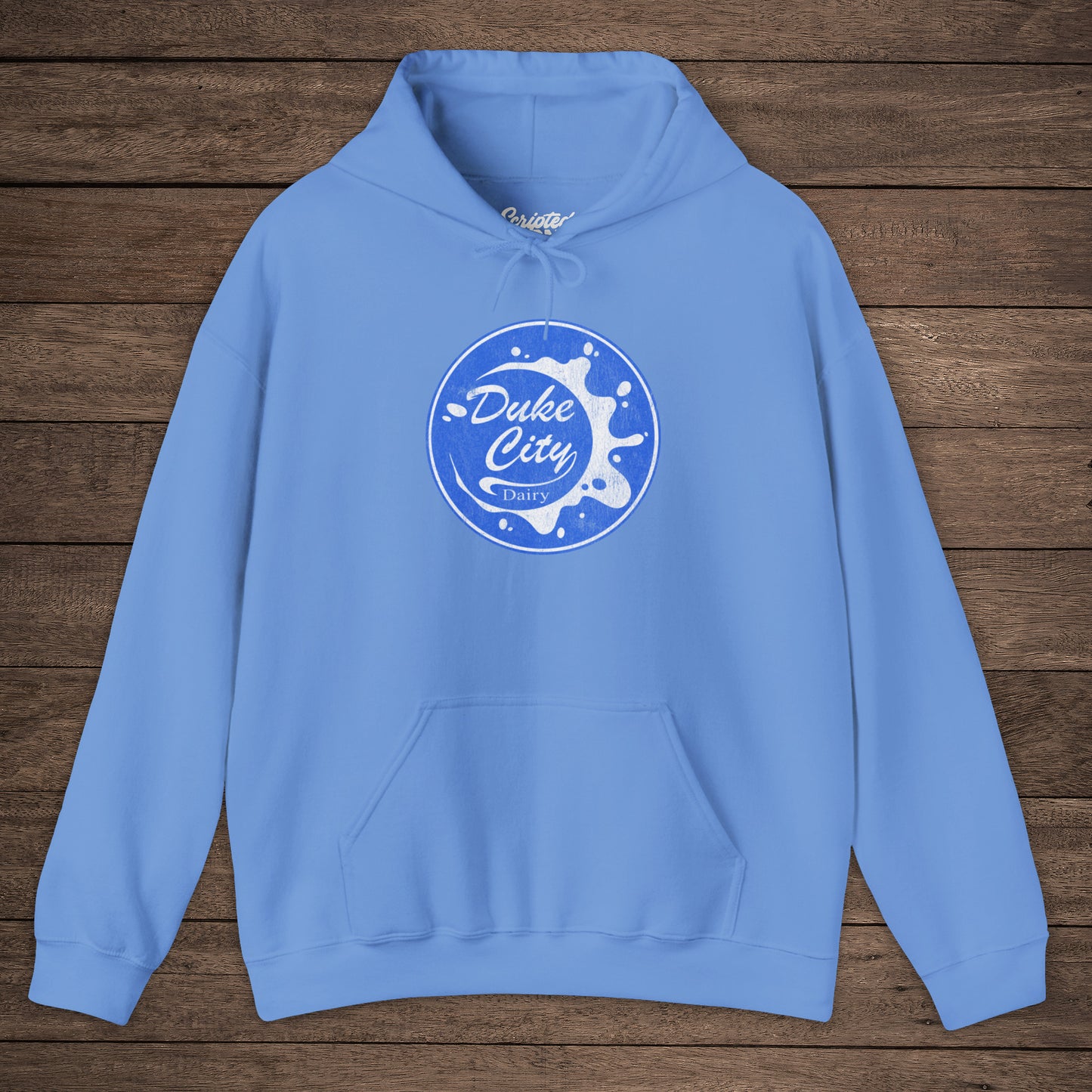 Light blue hoodie with 'Duke City Dairy' logo from Pluribus on a wooden background.