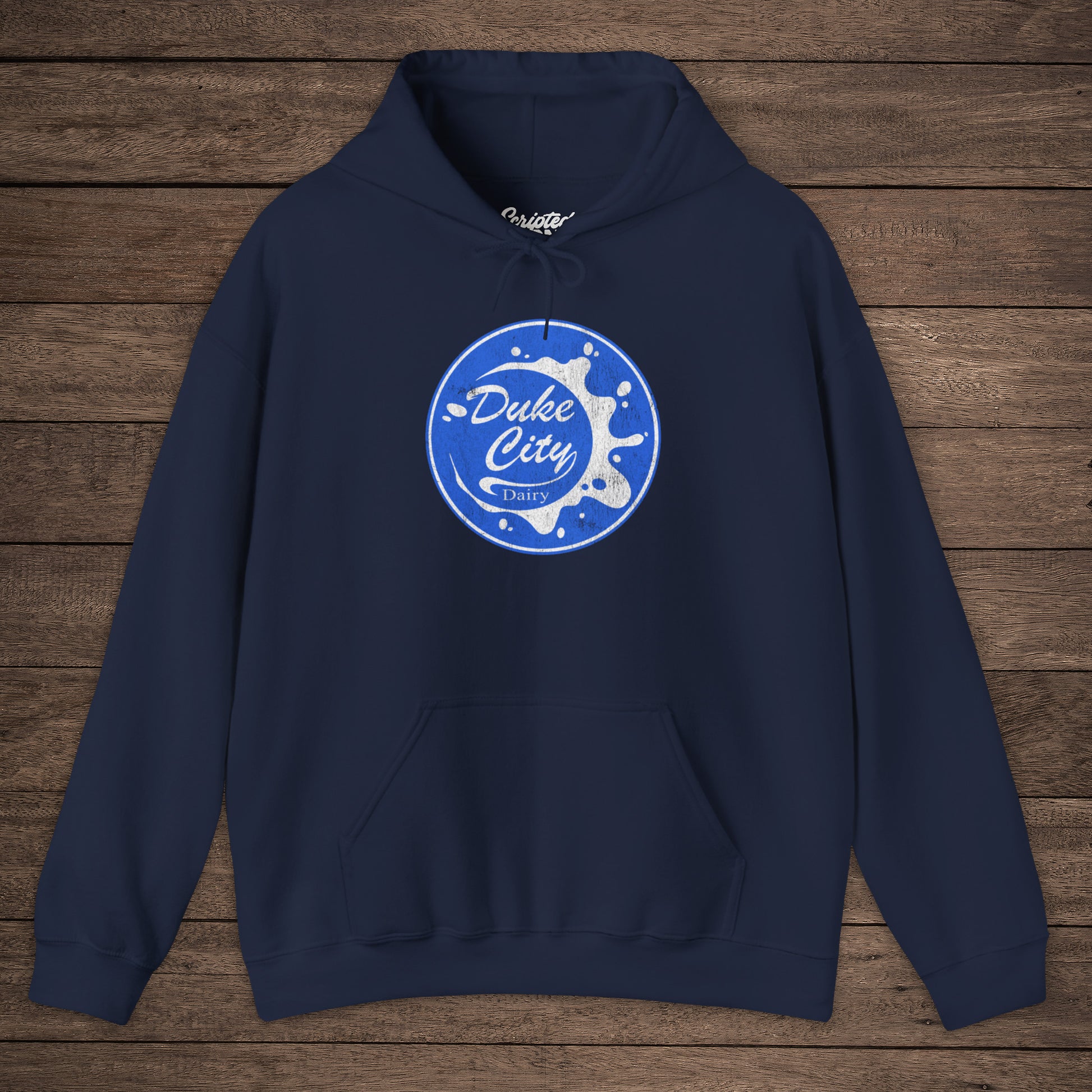 Navy blue hoodie with 'Duke City Dairy' logo from Pluribus on a wooden background.