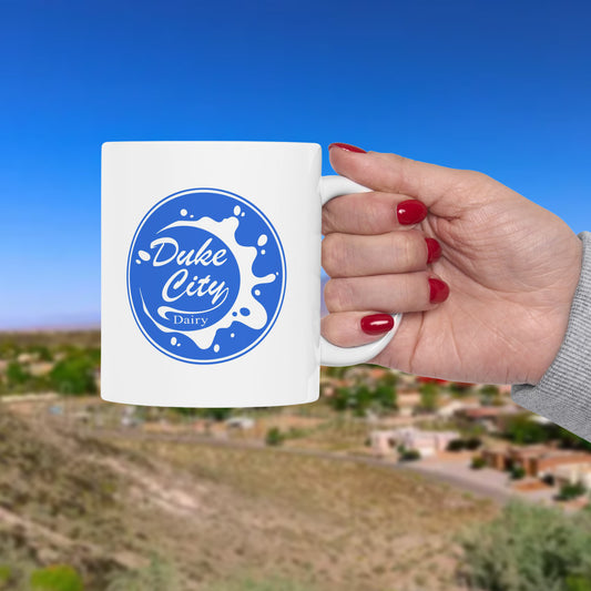 Hand holding a mug with 'Duke City Dairy' logo against a scenic background