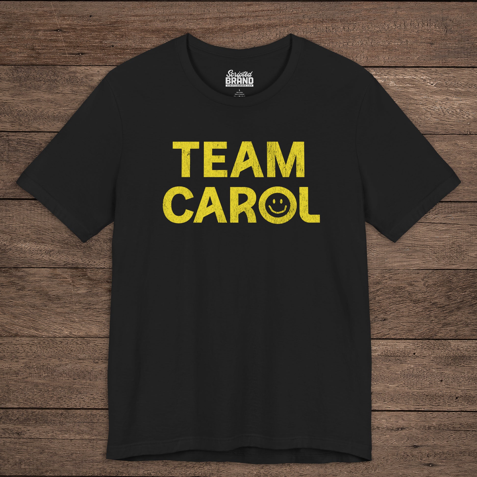 Front view of black TEAM CAROL t-shirt inspired by Pluribus with vintage distressed smiley face graphic in yellow