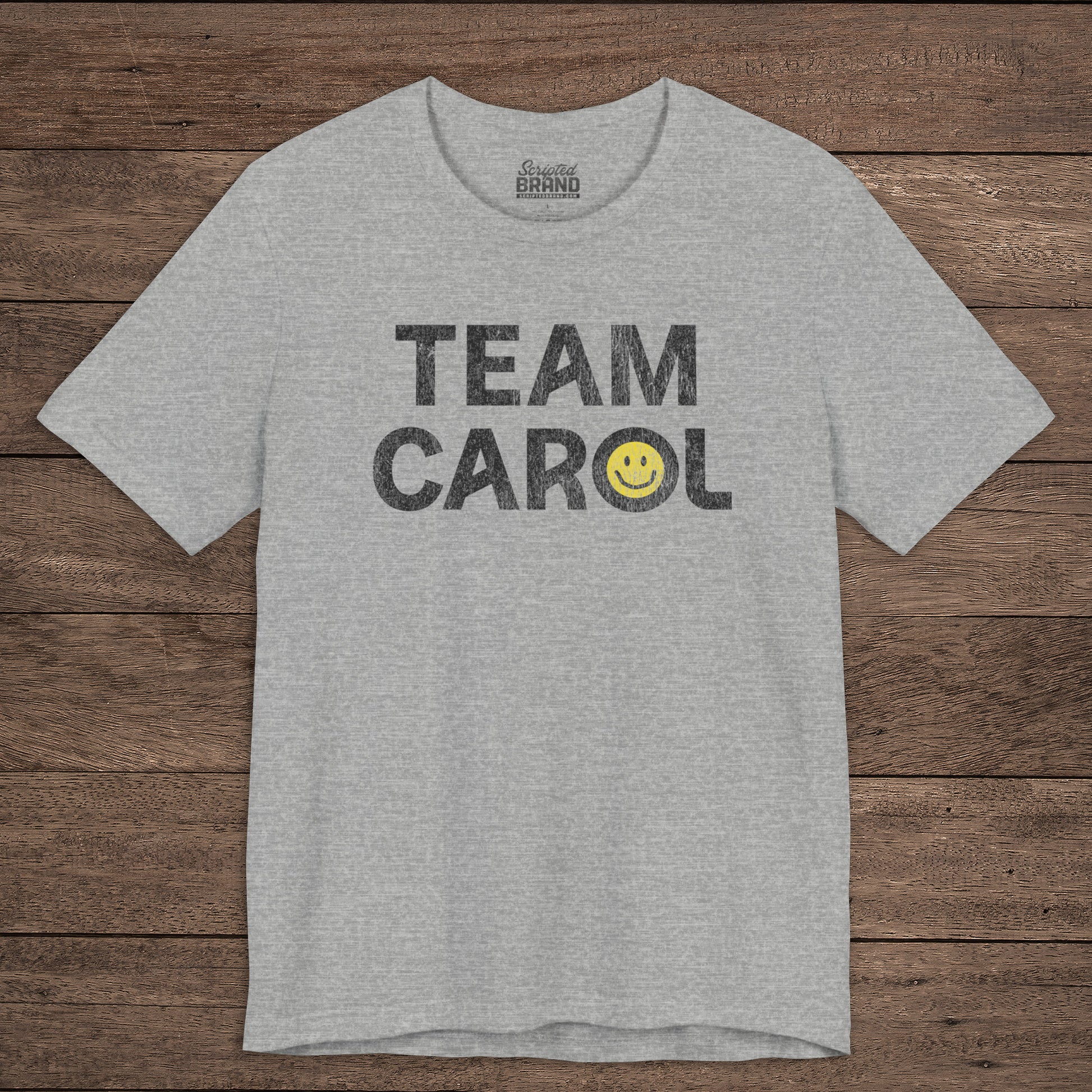 Front view of heather gray TEAM CAROL t-shirt inspired by Pluribus with vintage distressed smiley face graphic