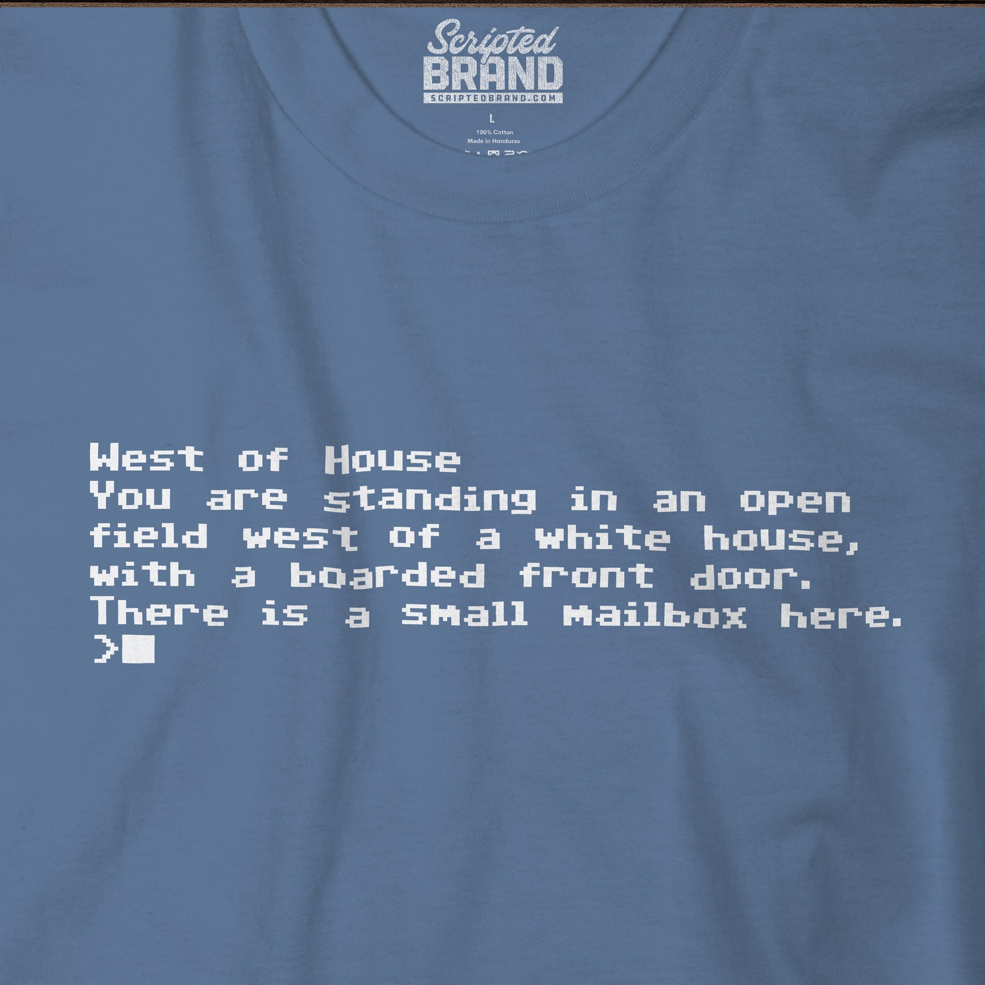 Closeup of blue Bella+Canvas 3001 Zork “West of House” text adventure quote t-shirt with terminal-style printed text